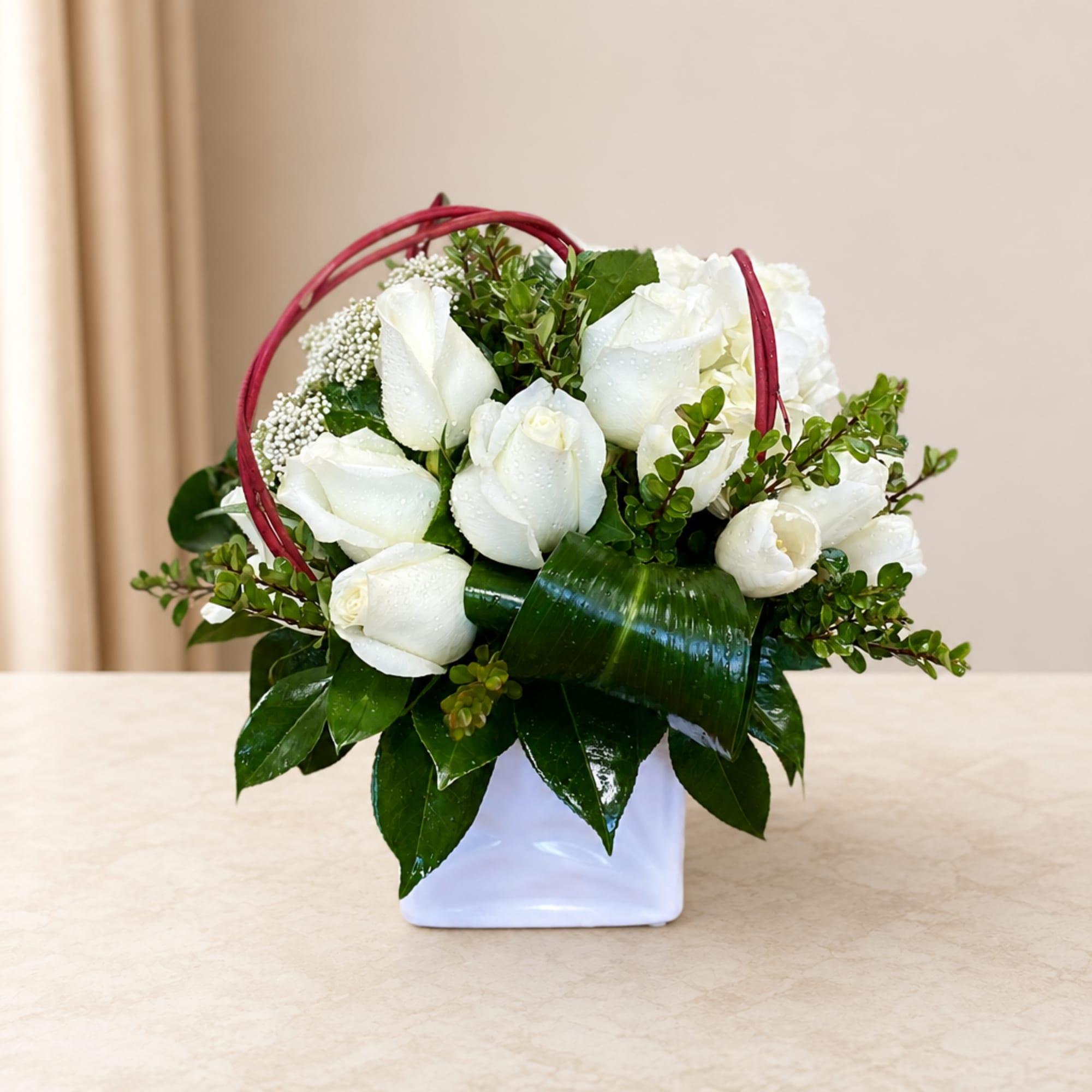 White rose arrangement in a white vase with a red handle