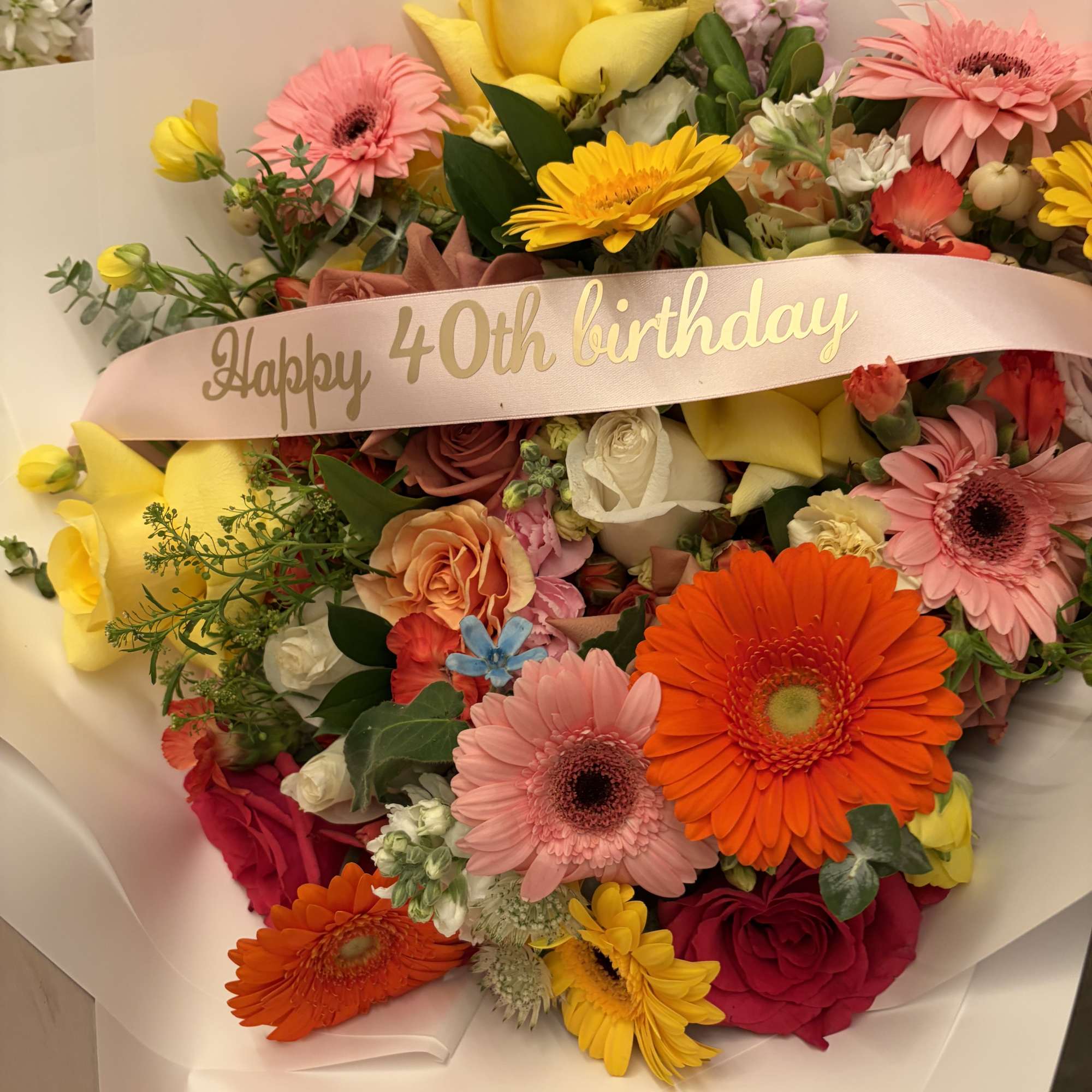Mixed bouquet with gerbera daisies, roses, and yellow calla lilies in pink wrap
