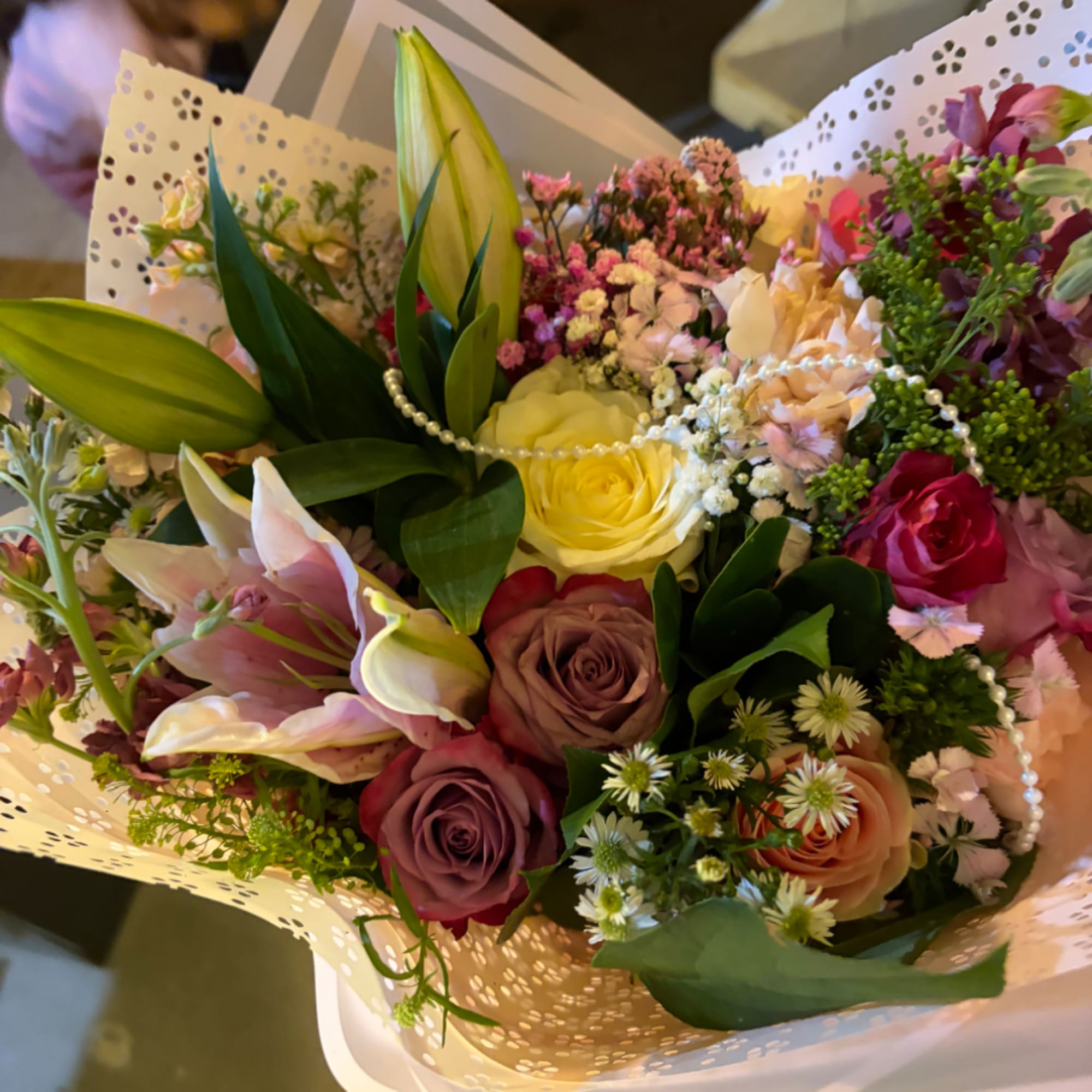 Mixed bouquet of roses and lilies wrapped in patterned paper
