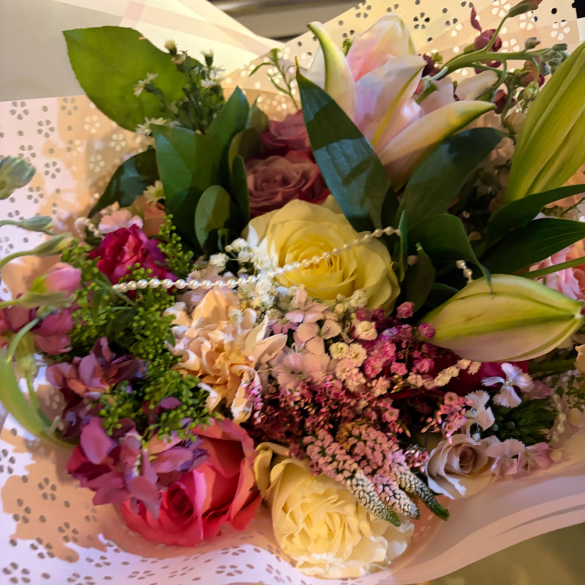 Mixed bouquet of roses and lilies in pastel wrapping