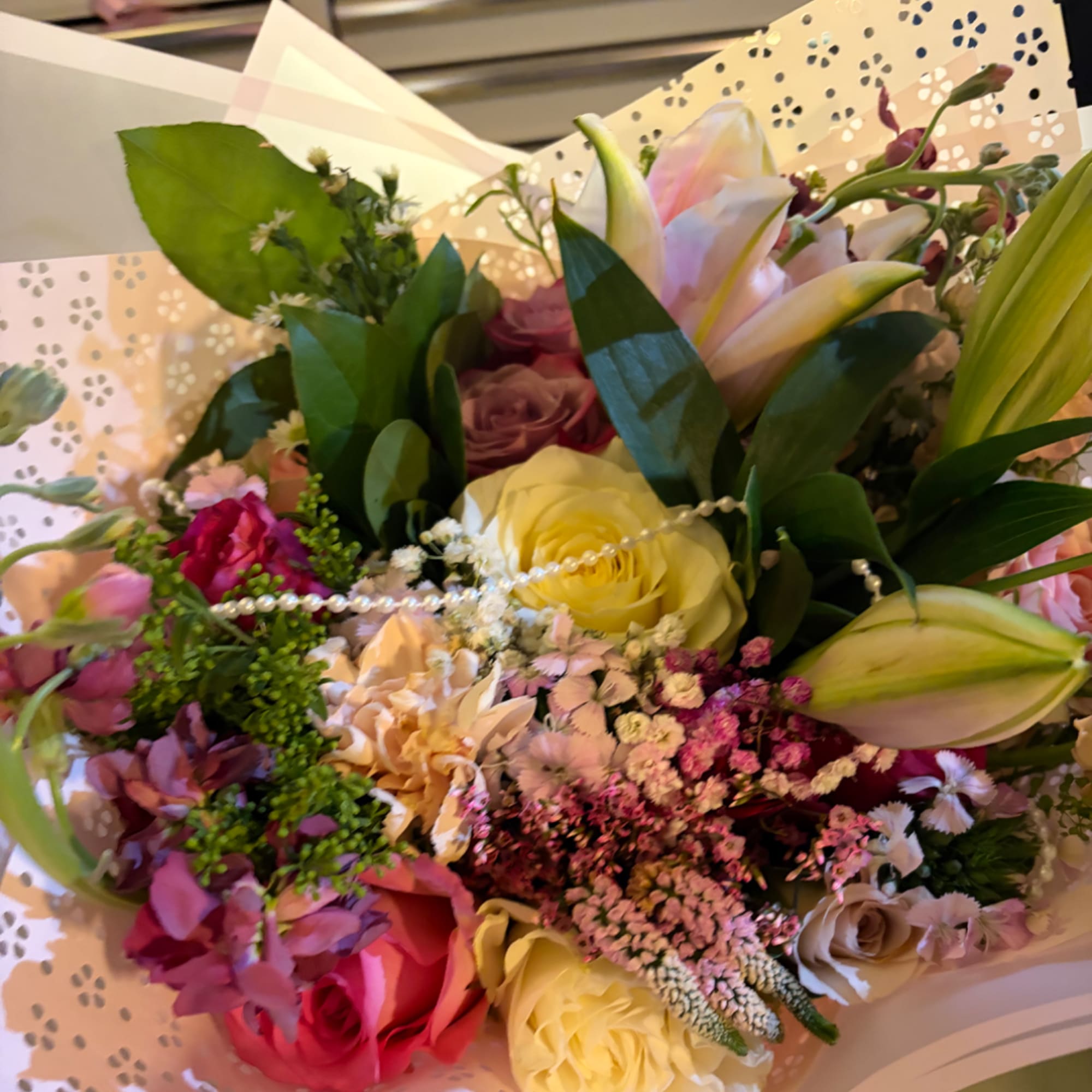 Mixed bouquet with roses and lilies wrapped in patterned paper
