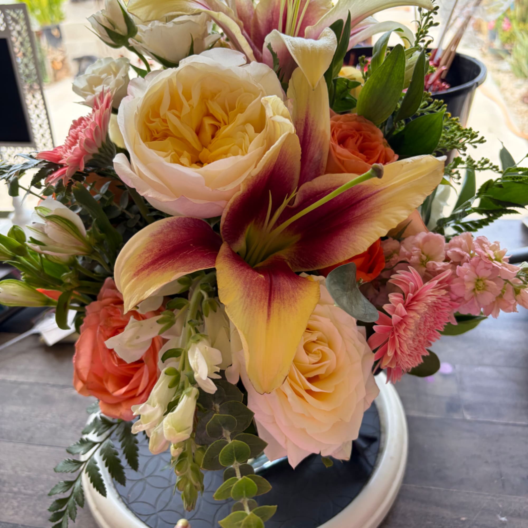Mixed bouquet with cream roses, pink lilies, and coral blooms in a vase