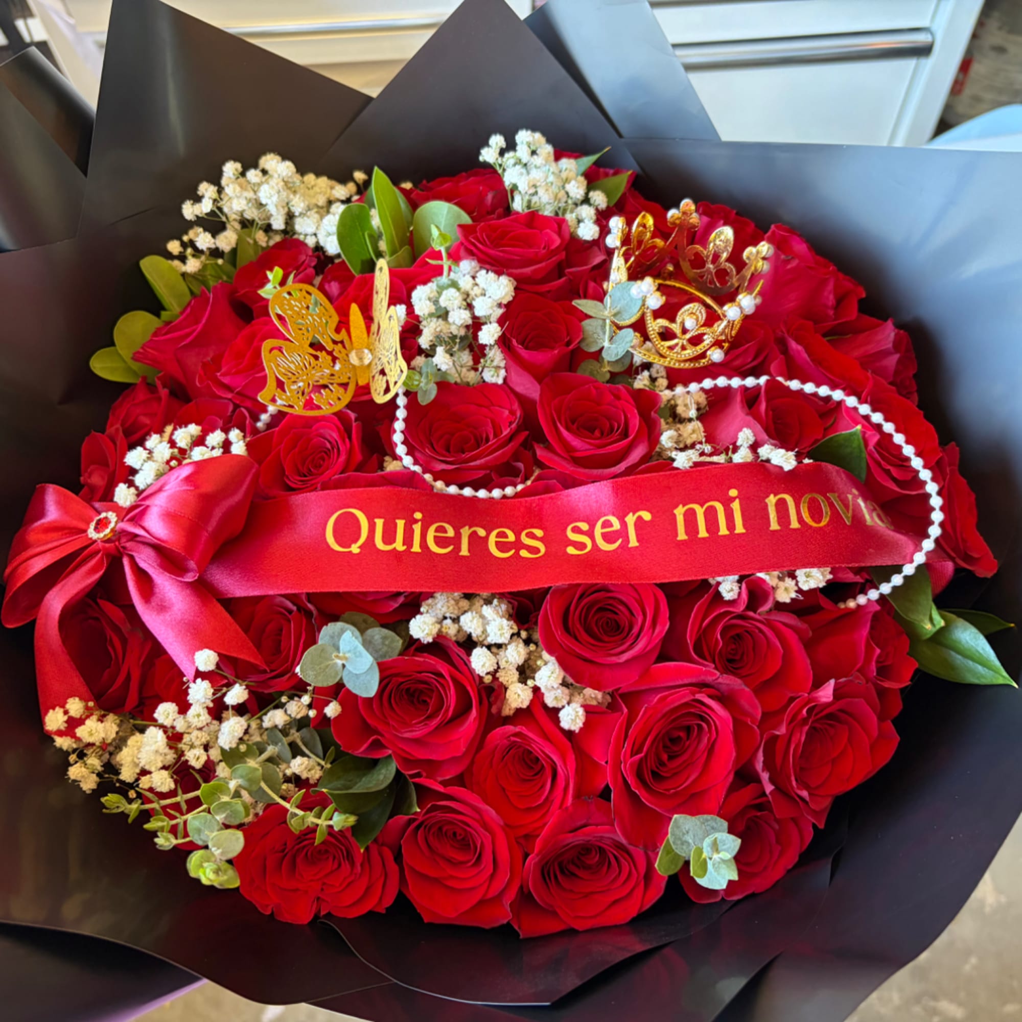 Bouquet of red roses with a red ribbon and gold crown decorations