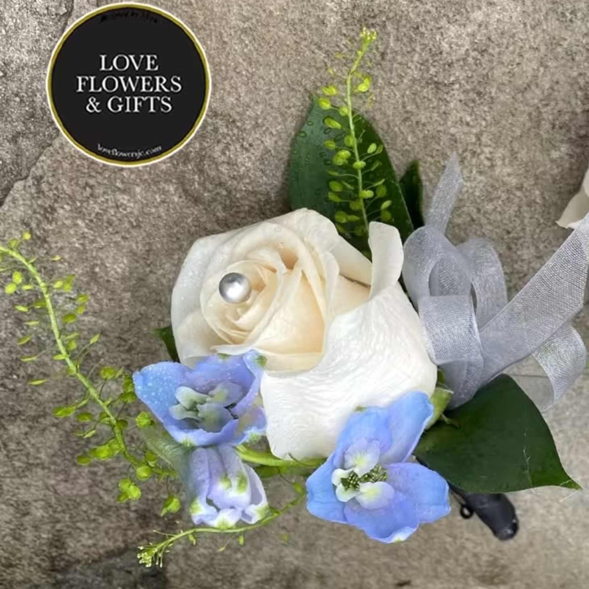 White rose and light blue flowers boutonniere with silver ribbon and pearl pin