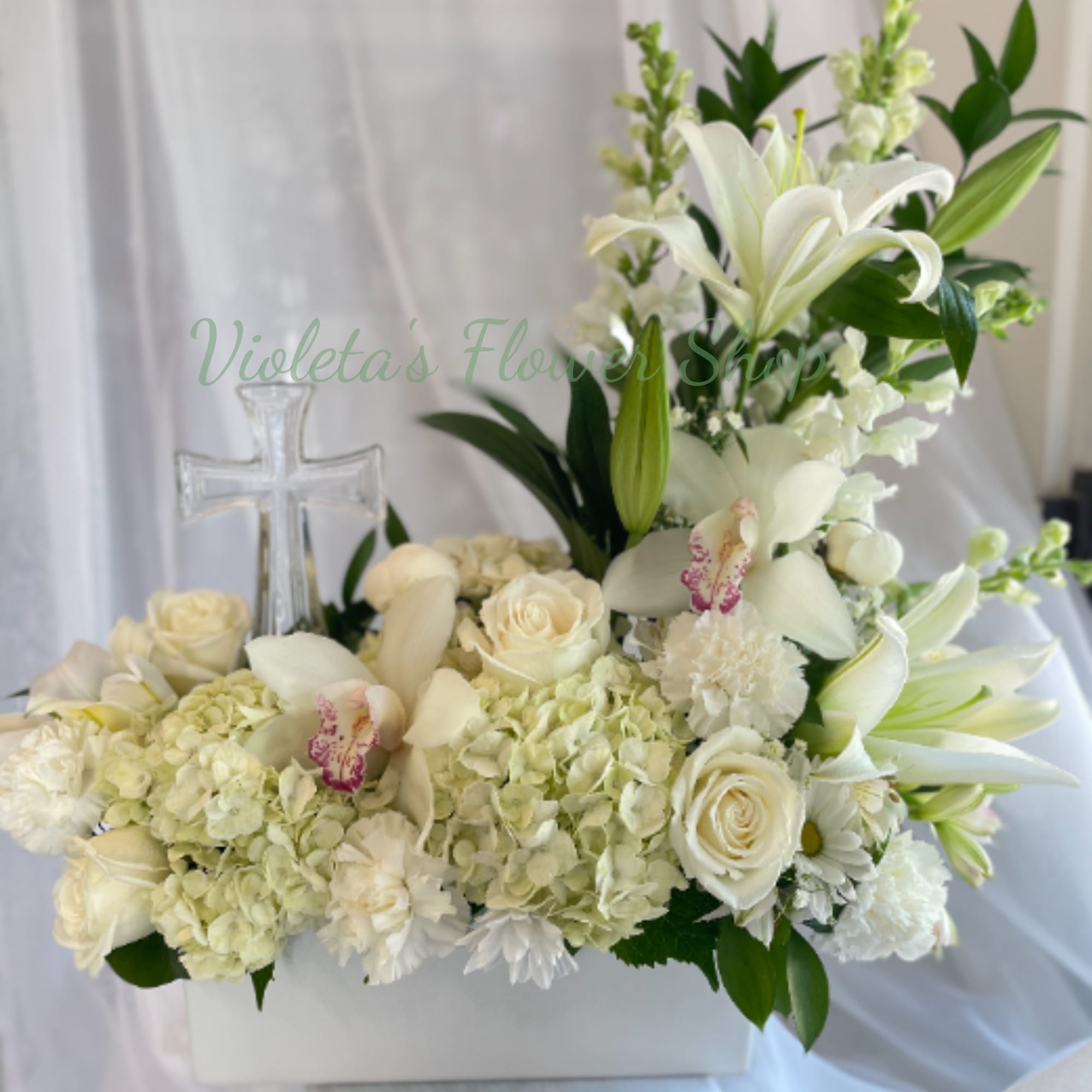 A serene, upright sympathy arrangement centered on pure white lilies and a