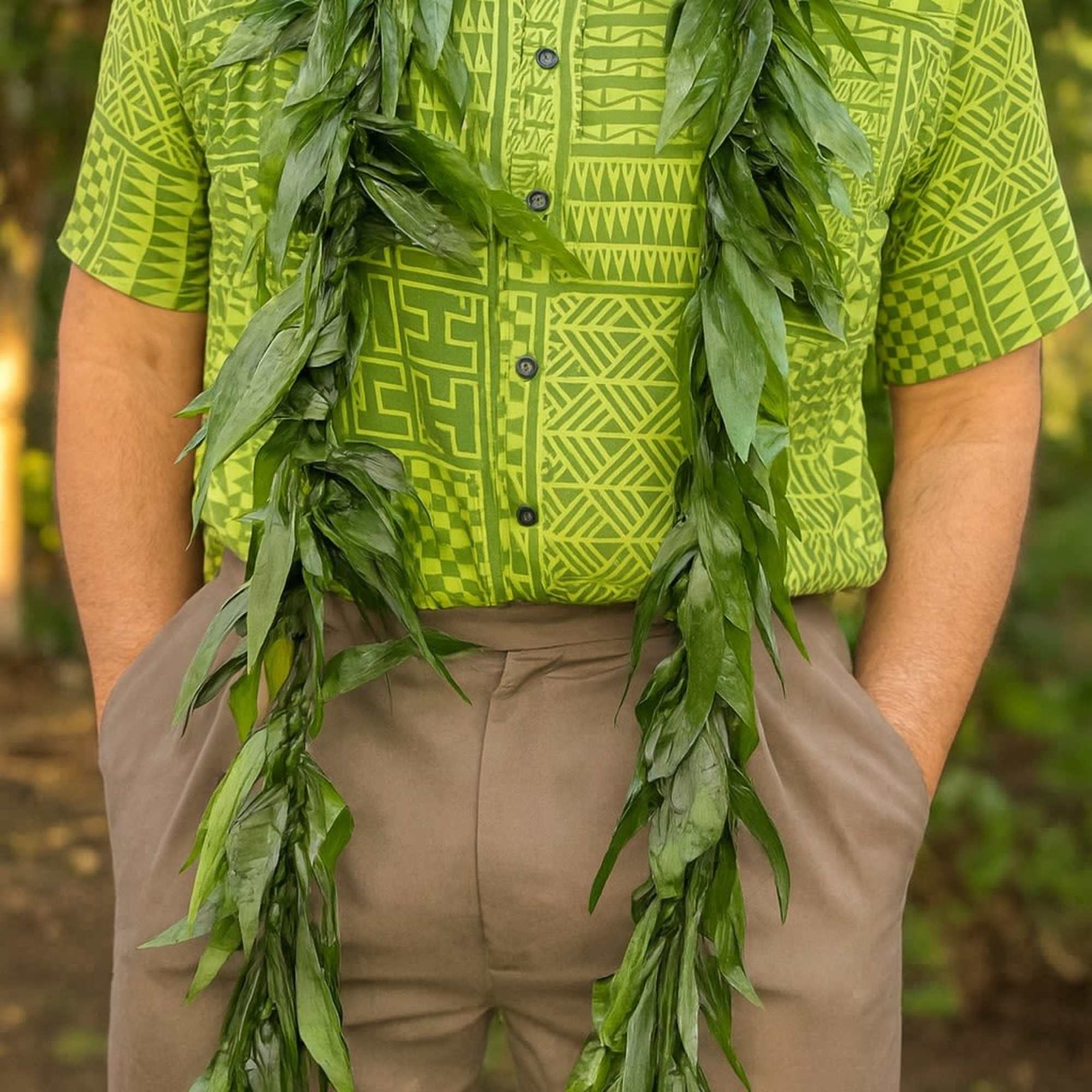 Long green foliage lei draped around a person in a lime patterned shirt