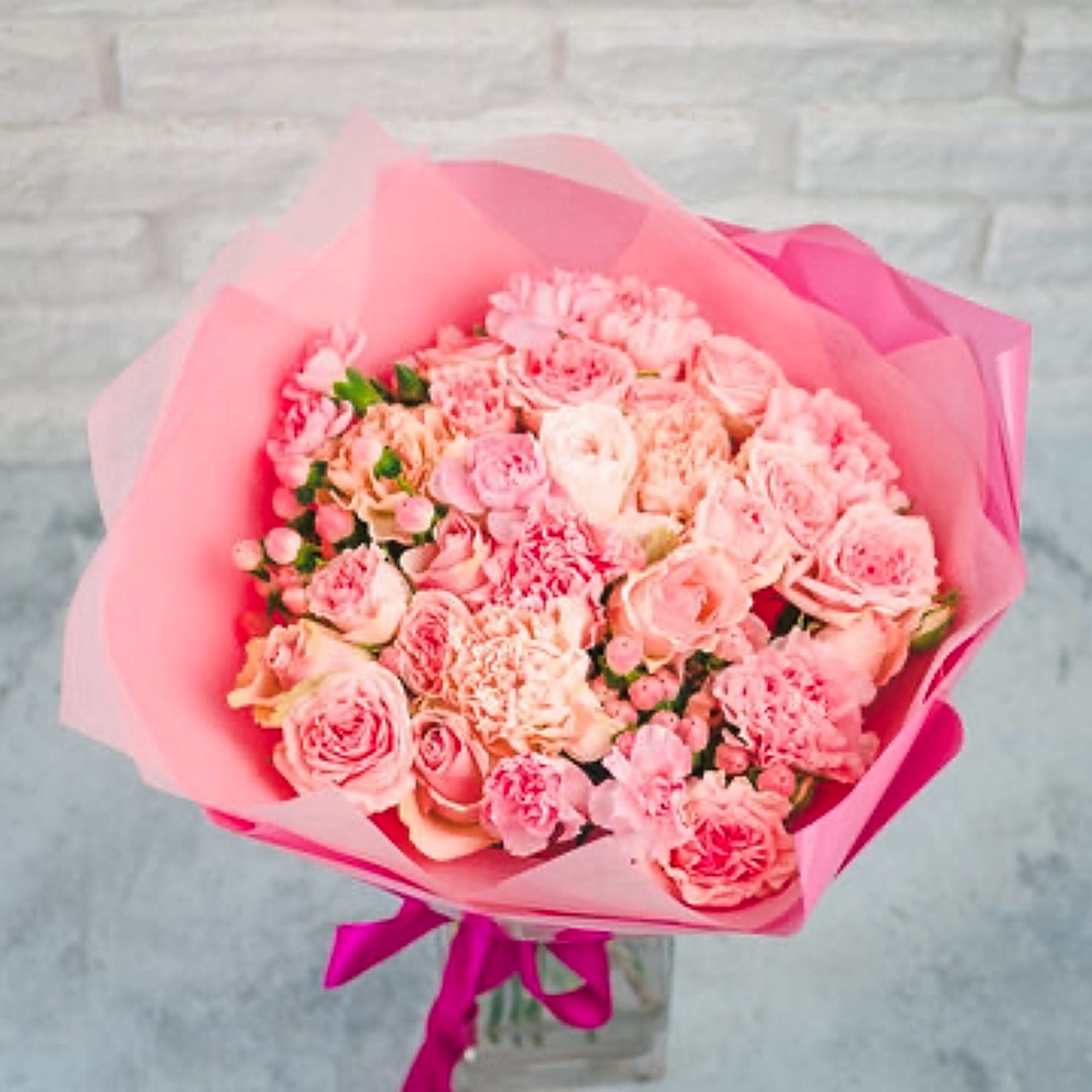 Pink bouquet of roses and carnations wrapped in pink paper