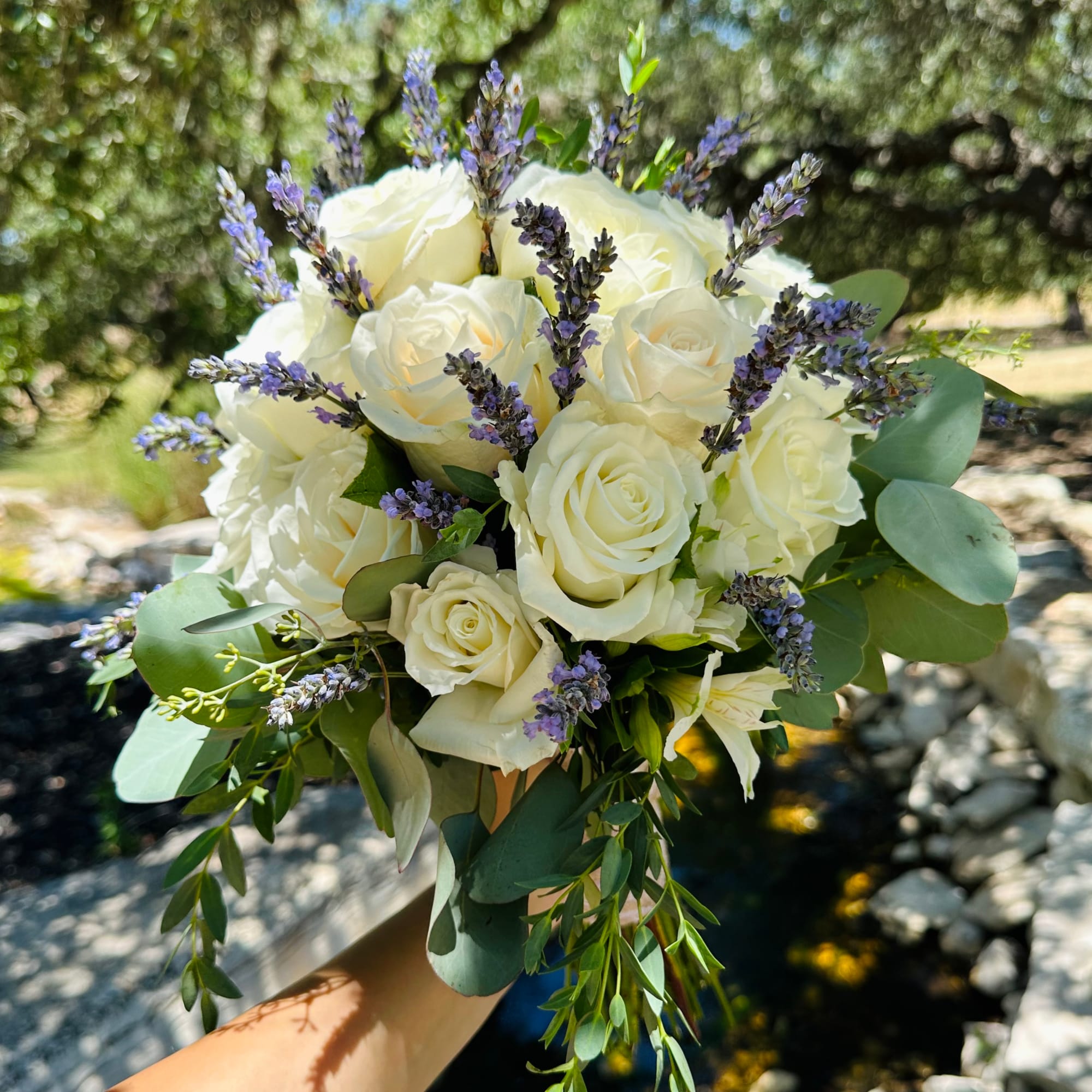 Bouquet of white roses with purple lavender sprigs and greenery