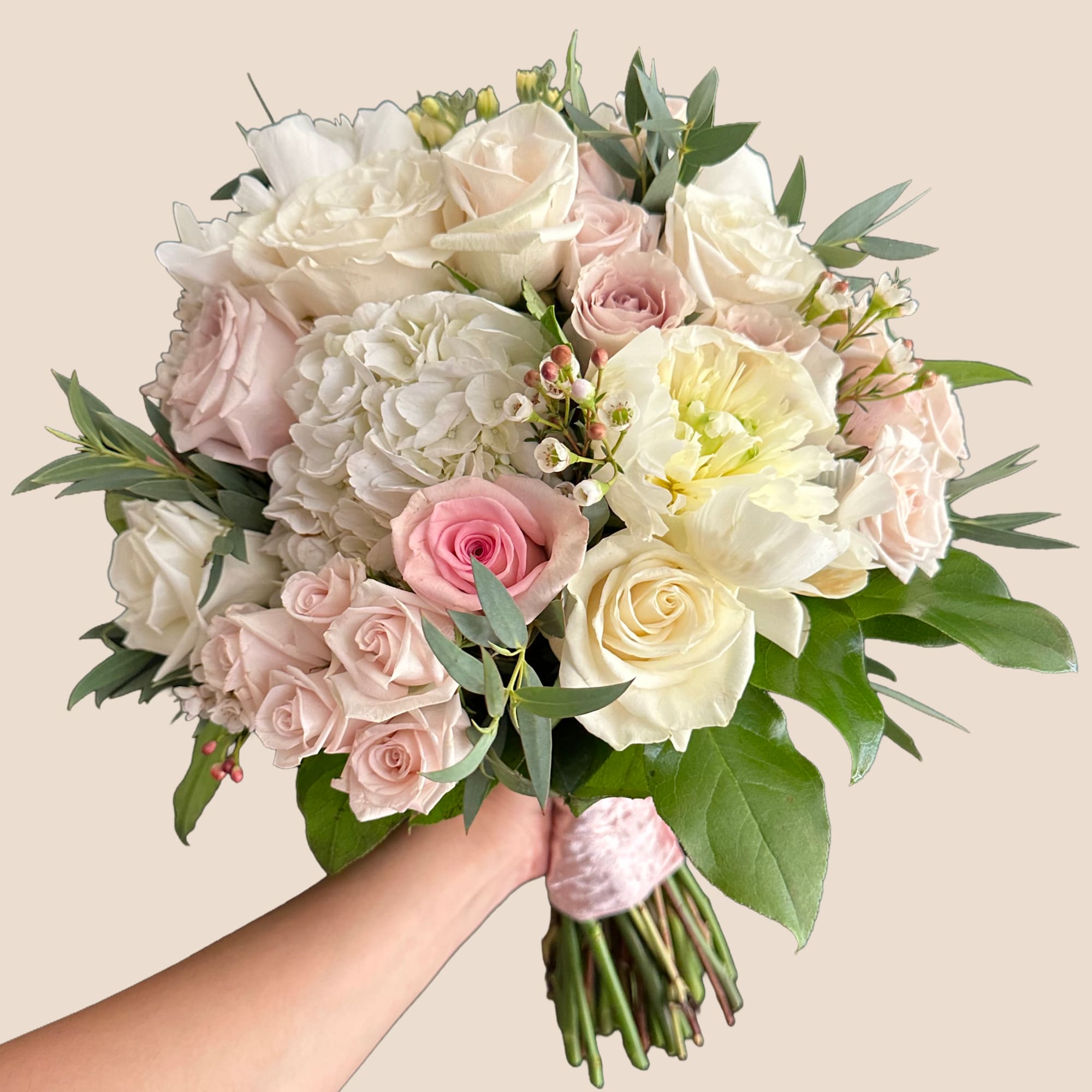 Handheld bouquet of pale pink and white roses with hydrangea and greenery