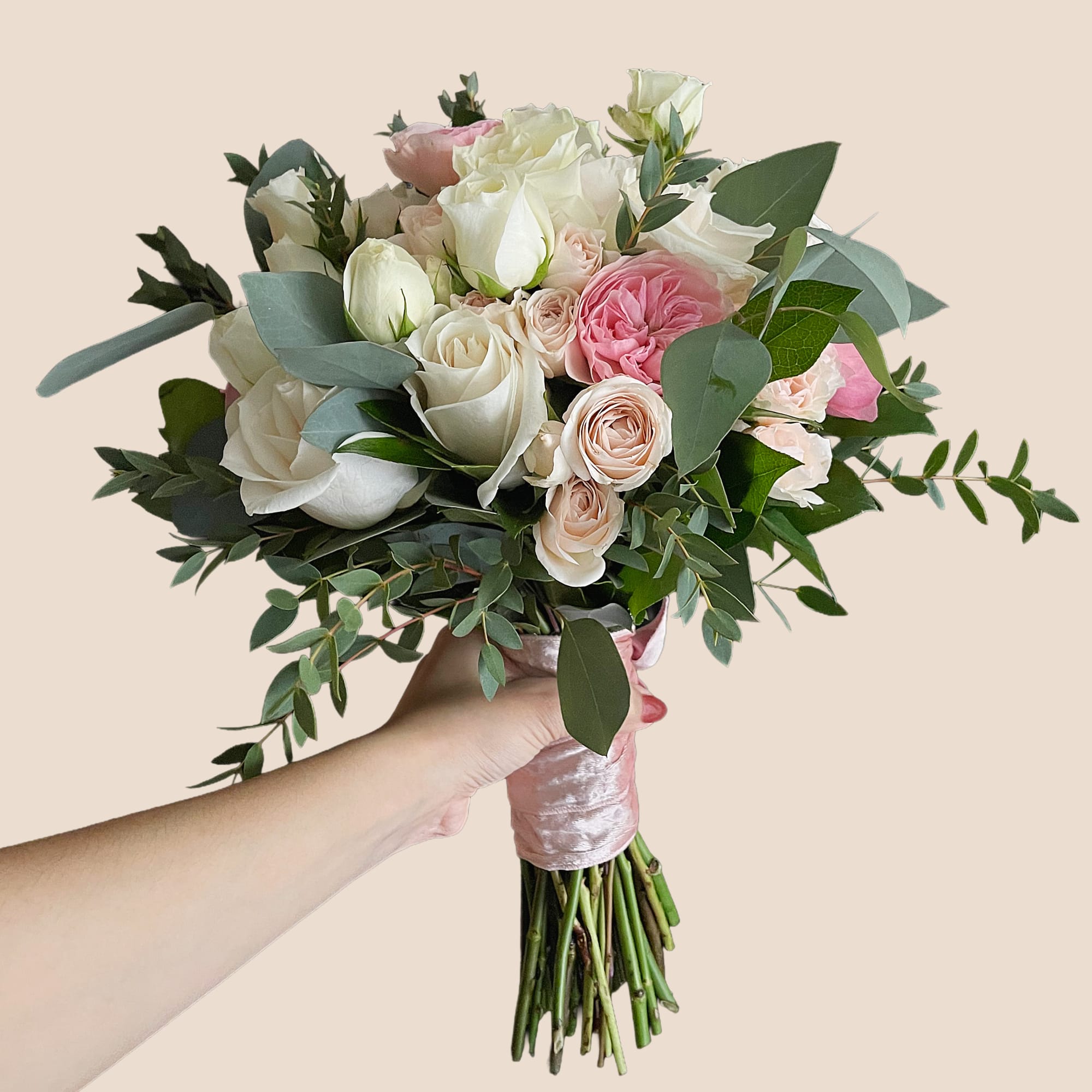 Handheld bouquet of white and pink roses with greenery
