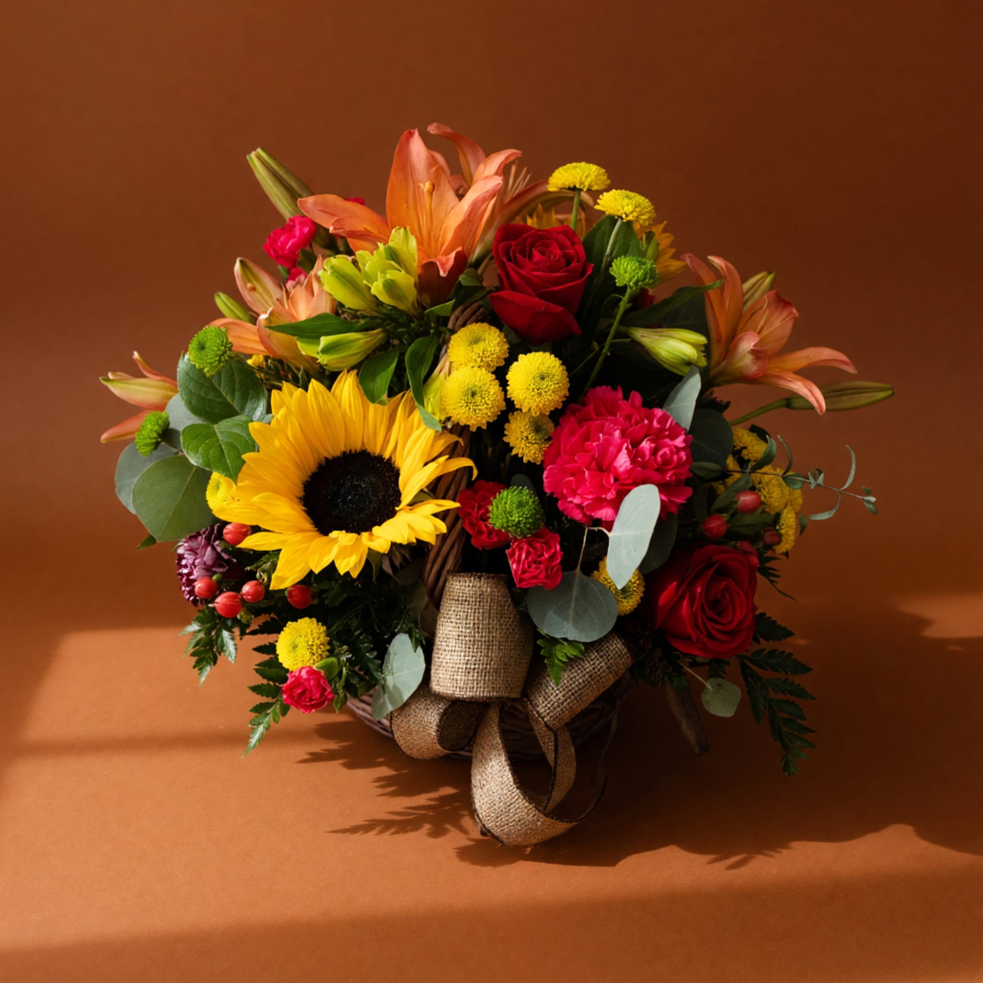 Mixed bouquet with sunflowers, roses, lilies, and carnations in a basket