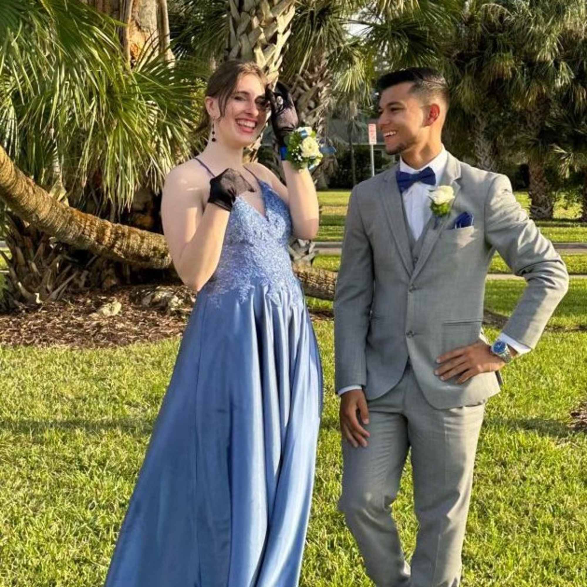 Couple in formal attire outdoors wearing matching white rose corsage and boutonniere