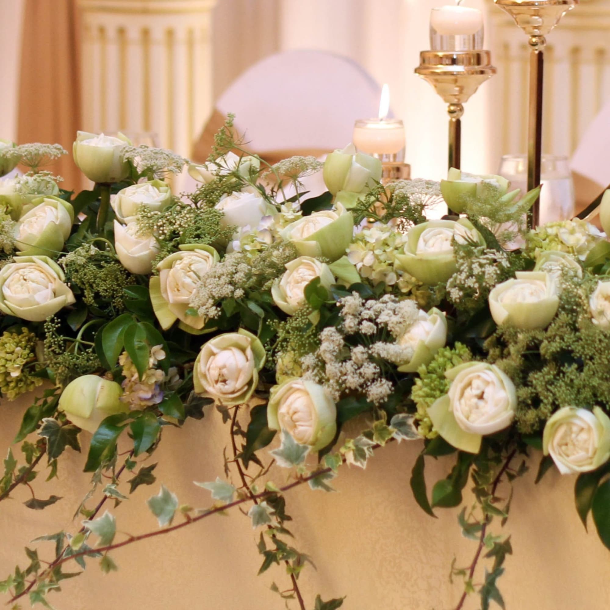 Low floral centerpiece with pale green and white roses on a table