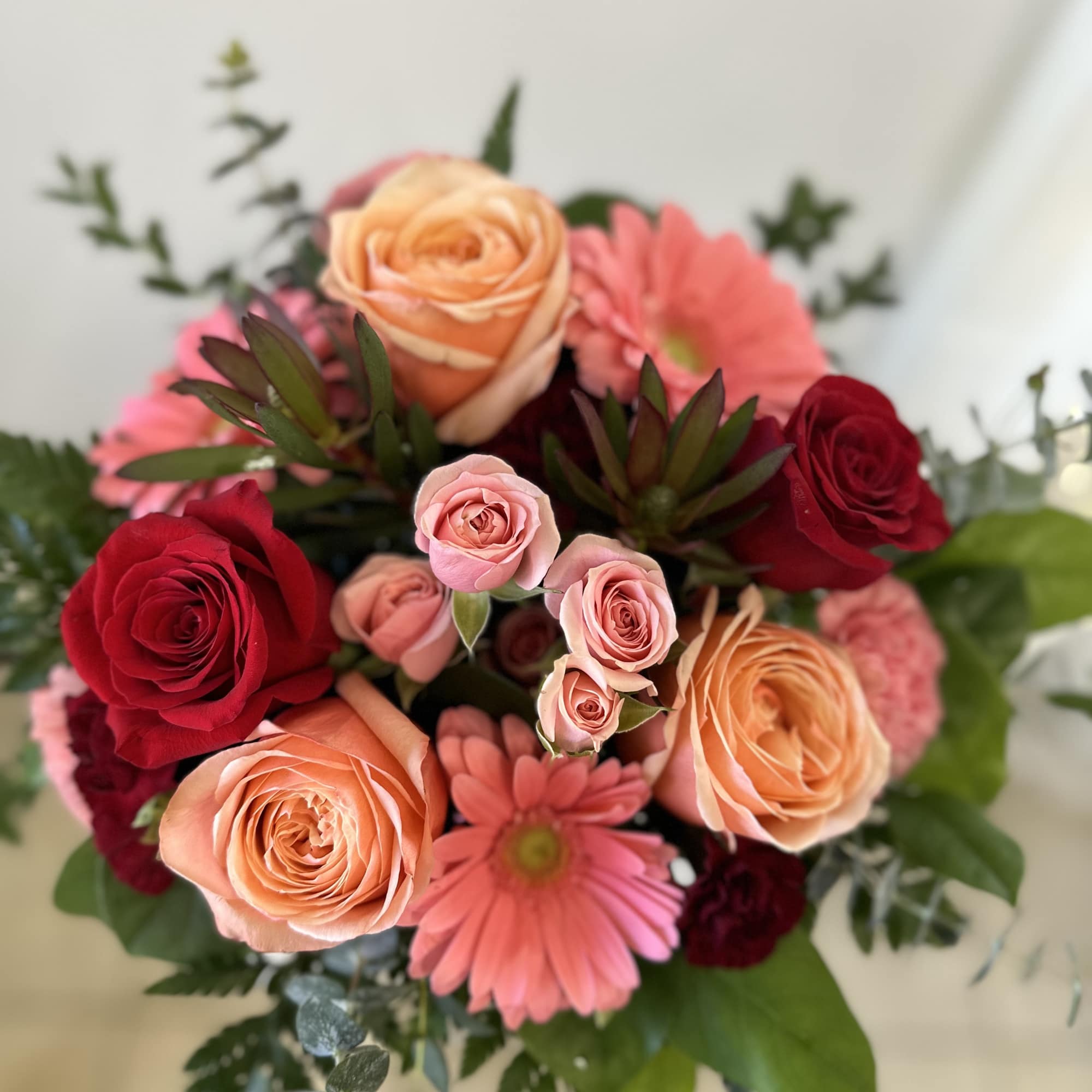 Bouquet of peach and red roses with pink daisies