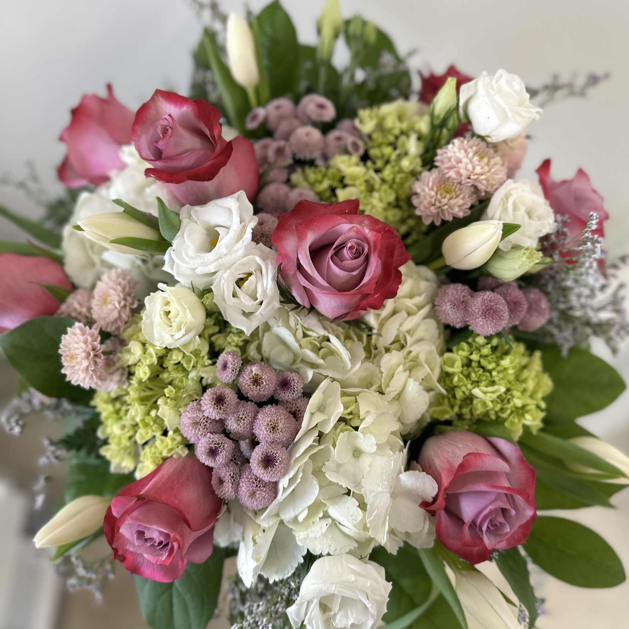 Bouquet of pink and white roses with hydrangeas and small lavender blooms