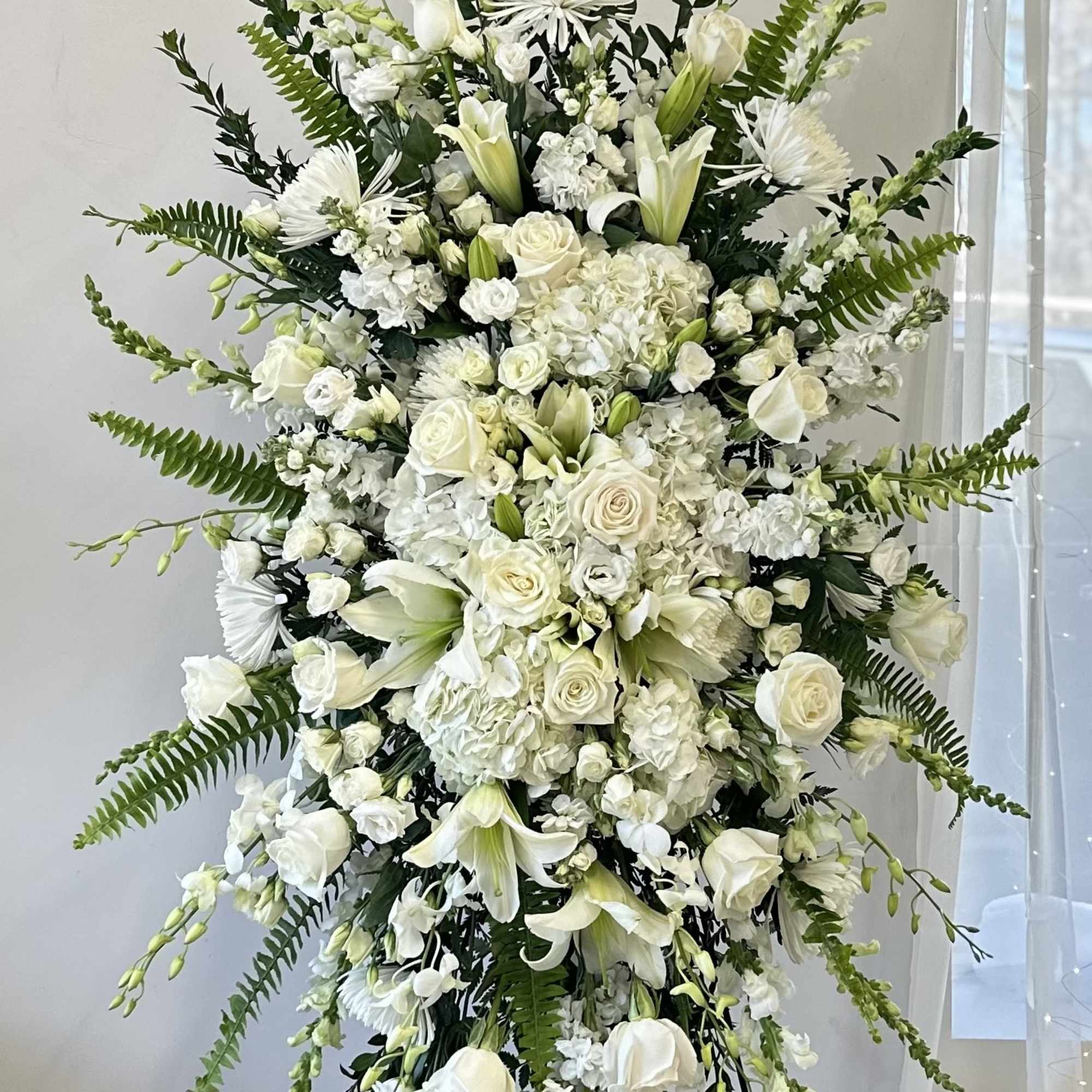 Tall white floral standing spray with roses, lilies, and chrysanthemums
