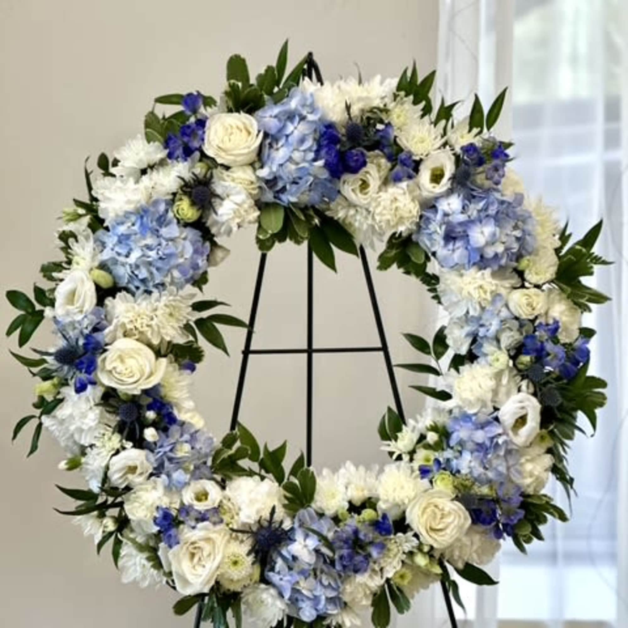 Blue and white floral wreath on a black stand