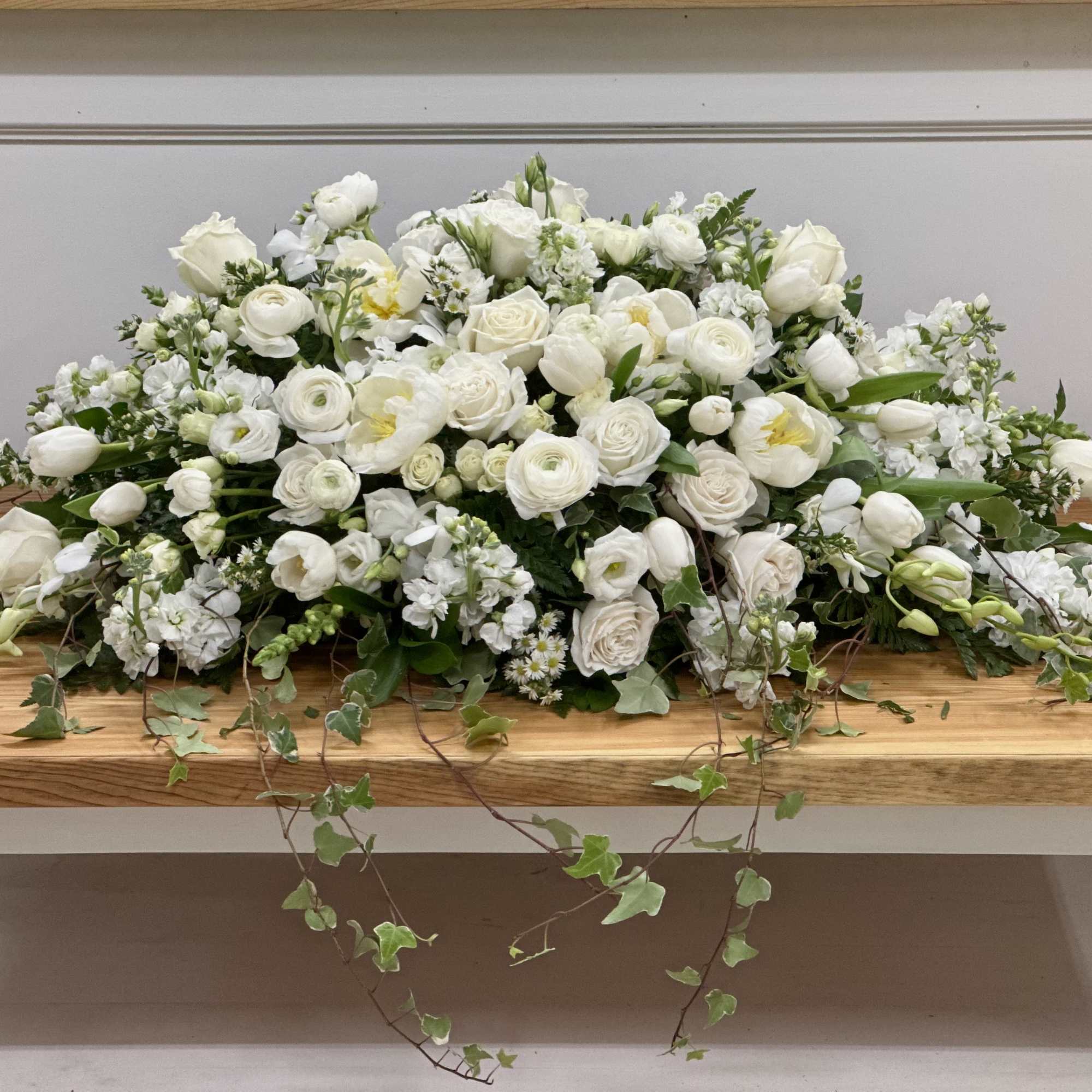 Large white floral arrangement with roses and tulips on a wooden table