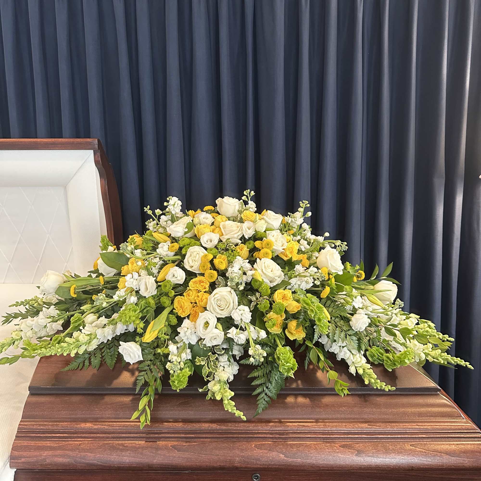 White and yellow floral spray on a casket