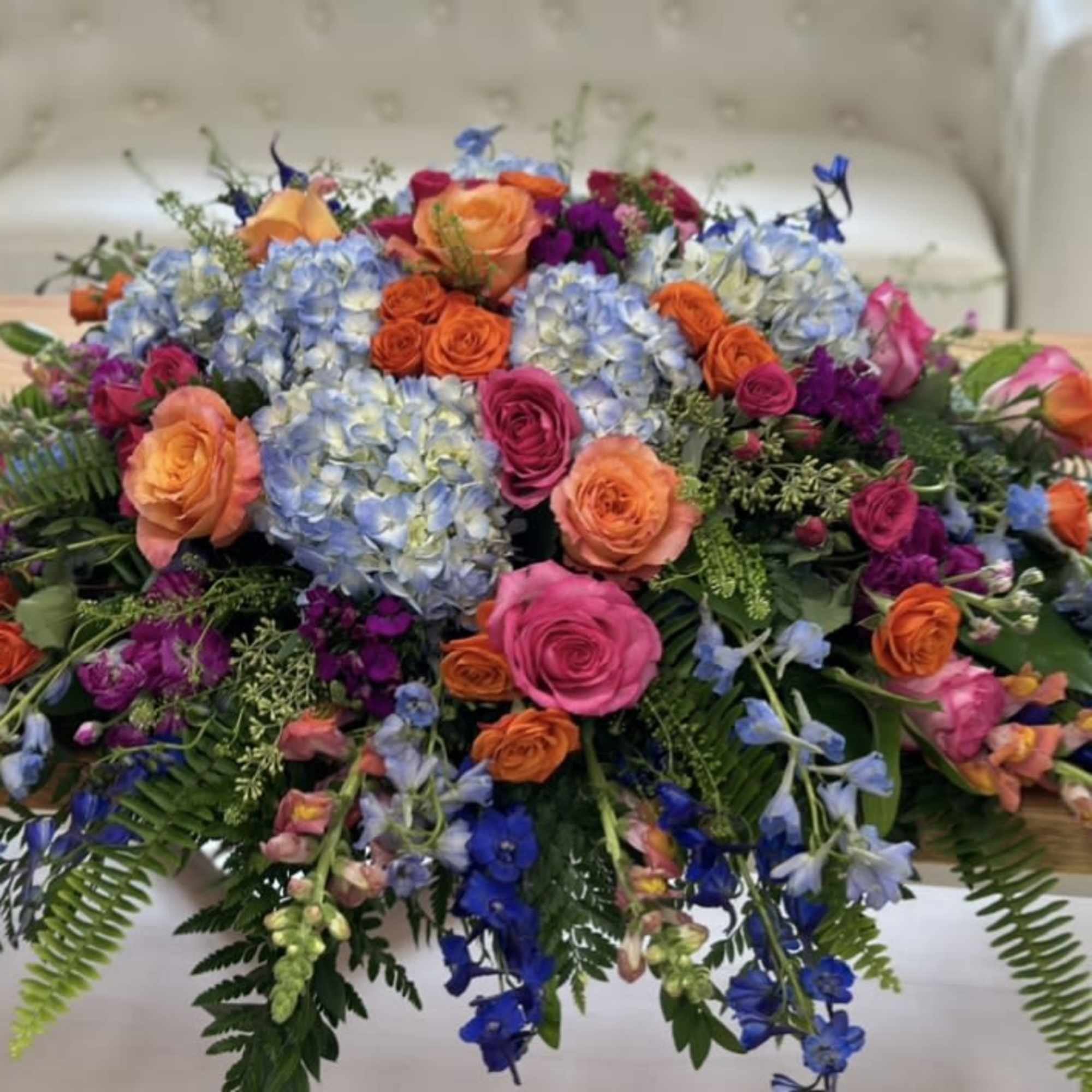 Large colorful floral centerpiece with roses, hydrangeas, and blue flowers
