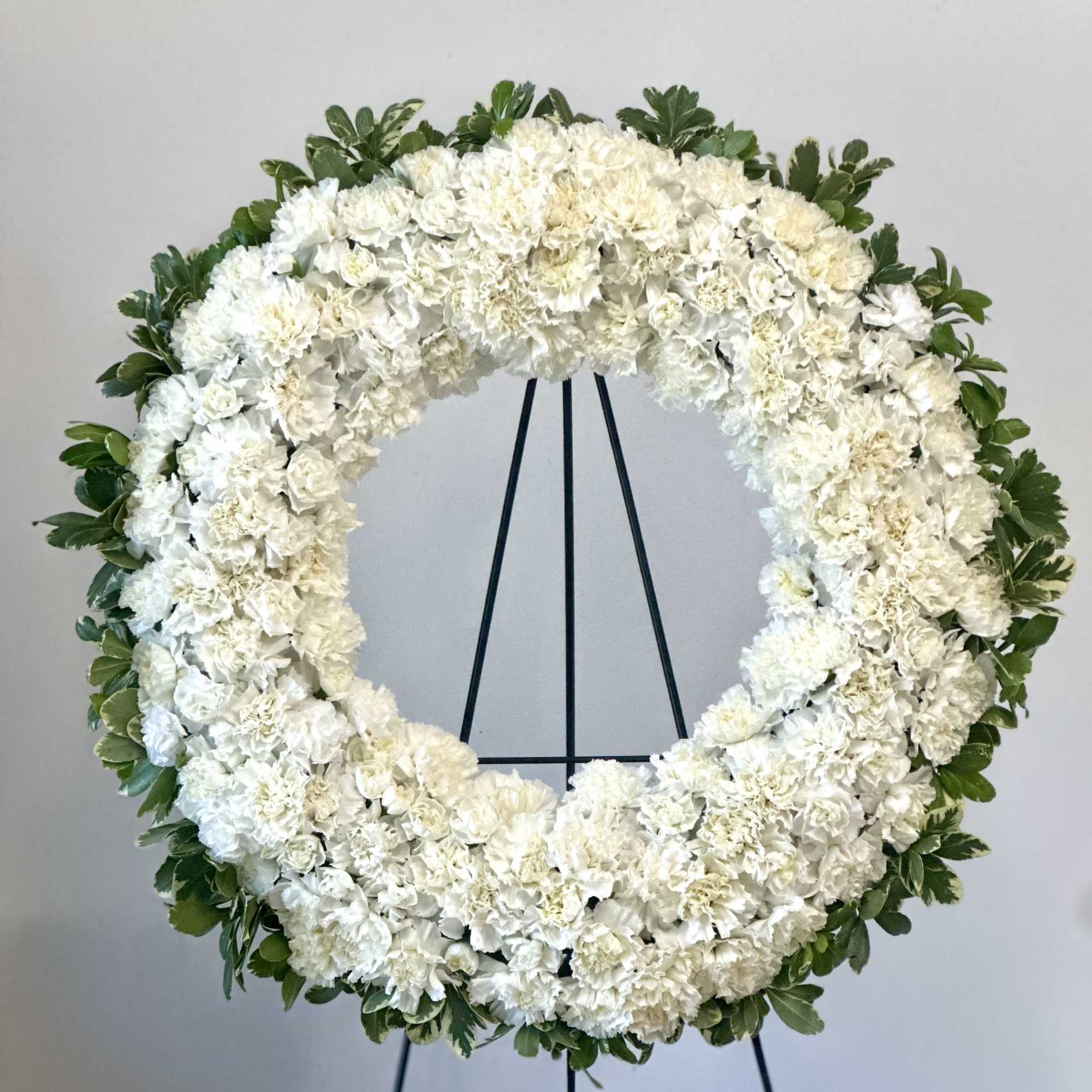 White floral wreath on a black stand