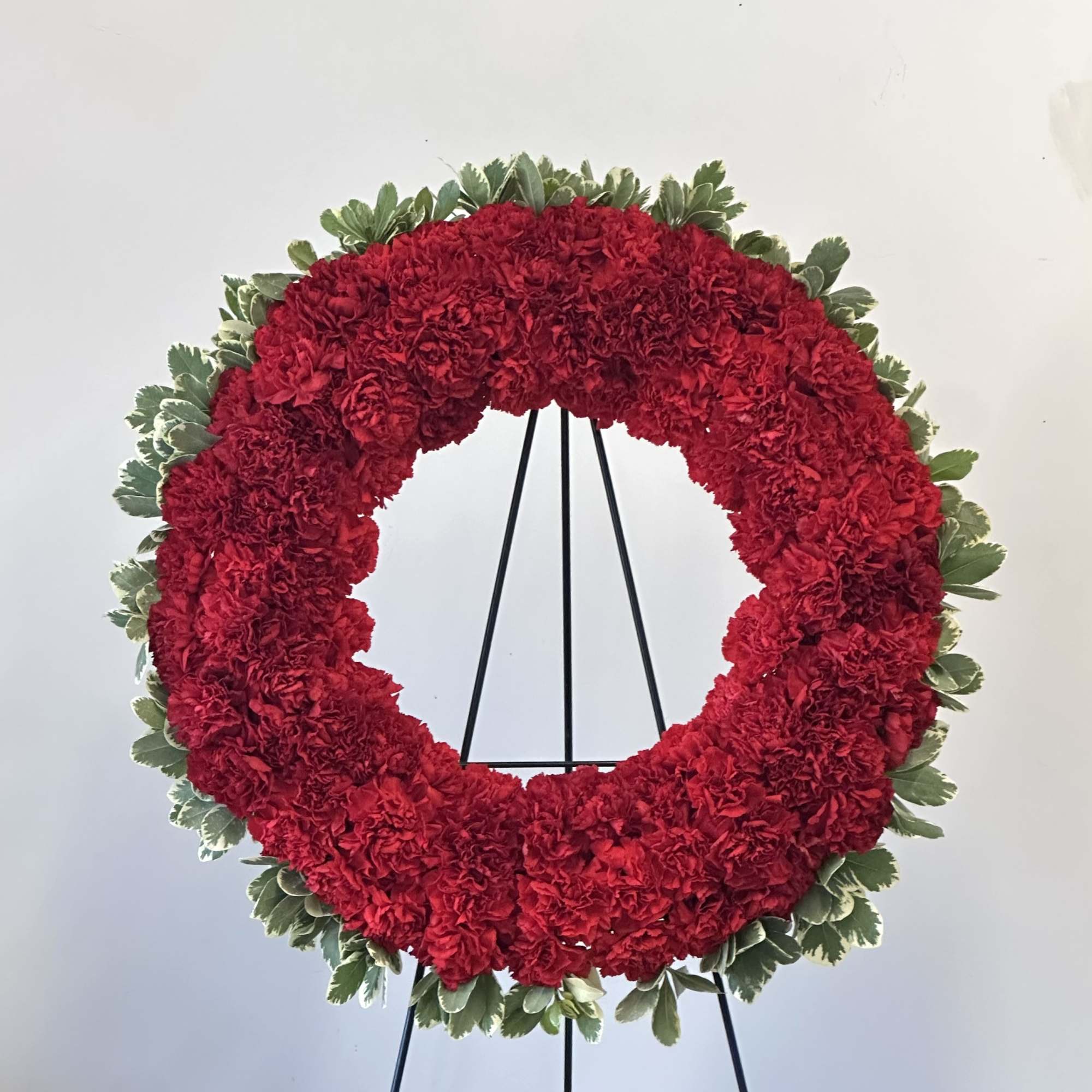 Red carnation wreath on a black easel with green edging