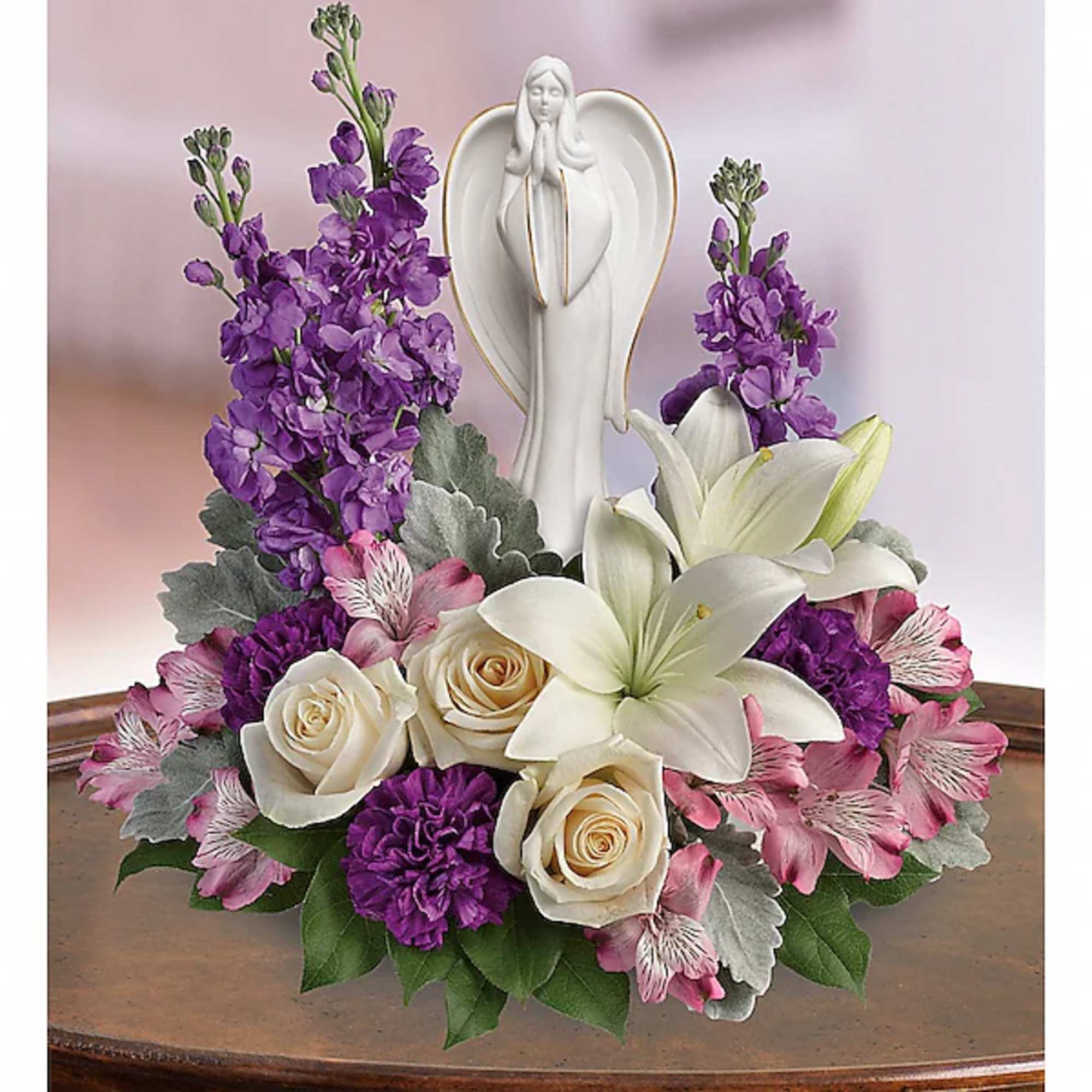 White angel figurine surrounded by purple and pink flowers
