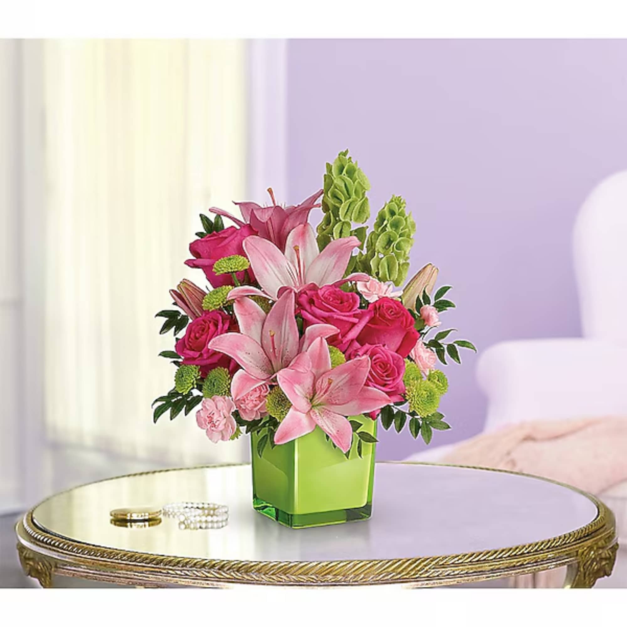 Pink lilies and roses arranged in a green square vase