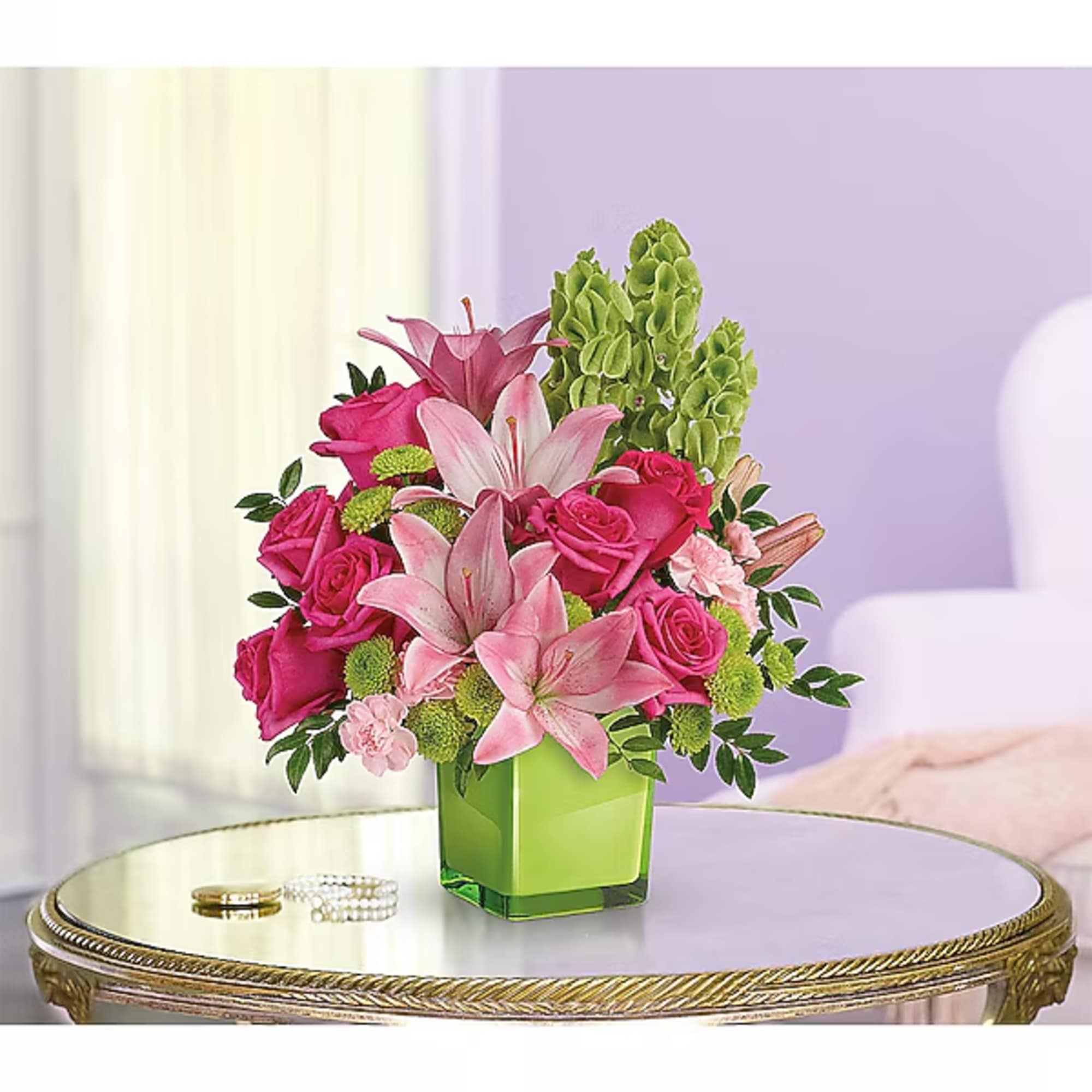 Pink lilies and roses arranged in a green square vase