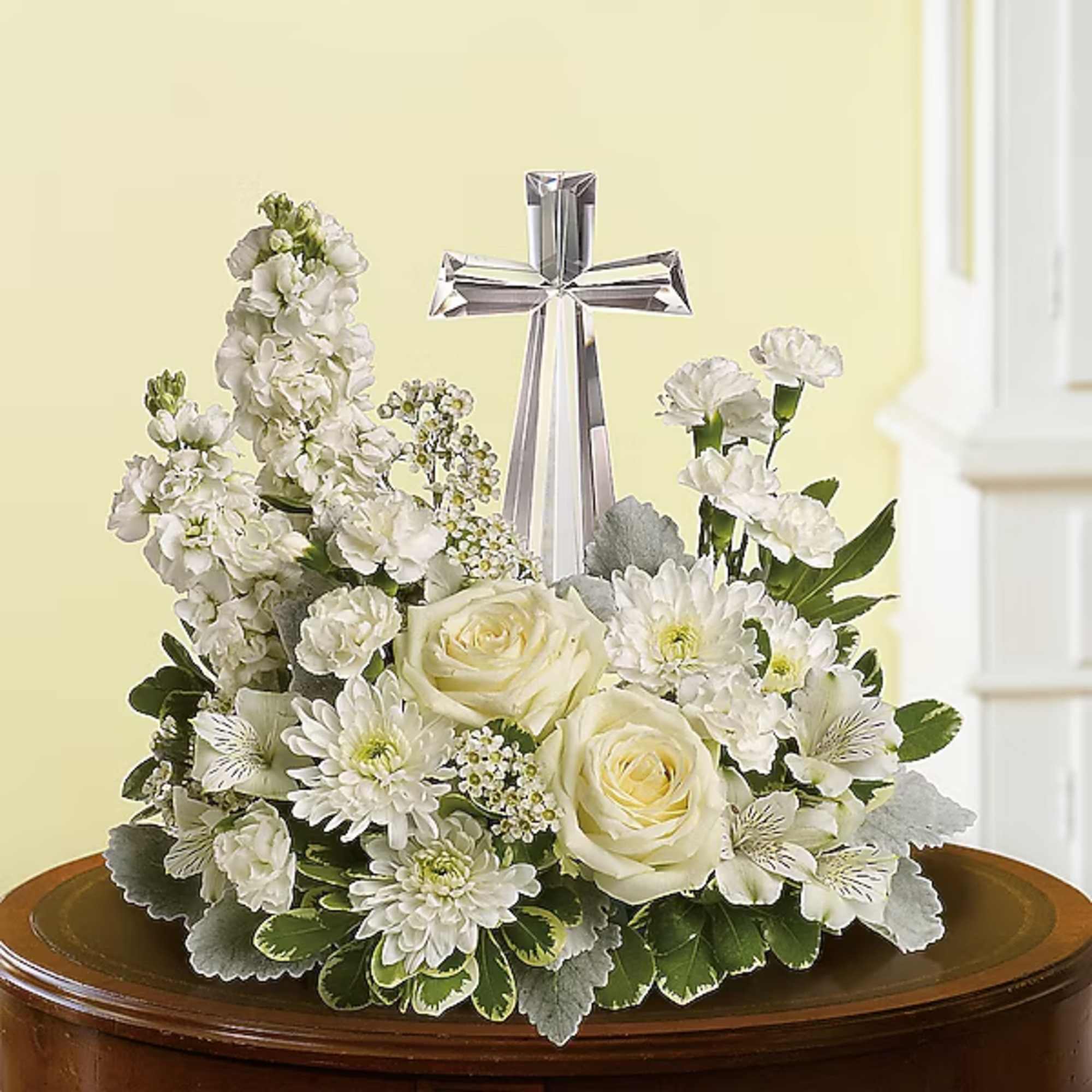 White floral arrangement with roses and a silver cross centerpiece