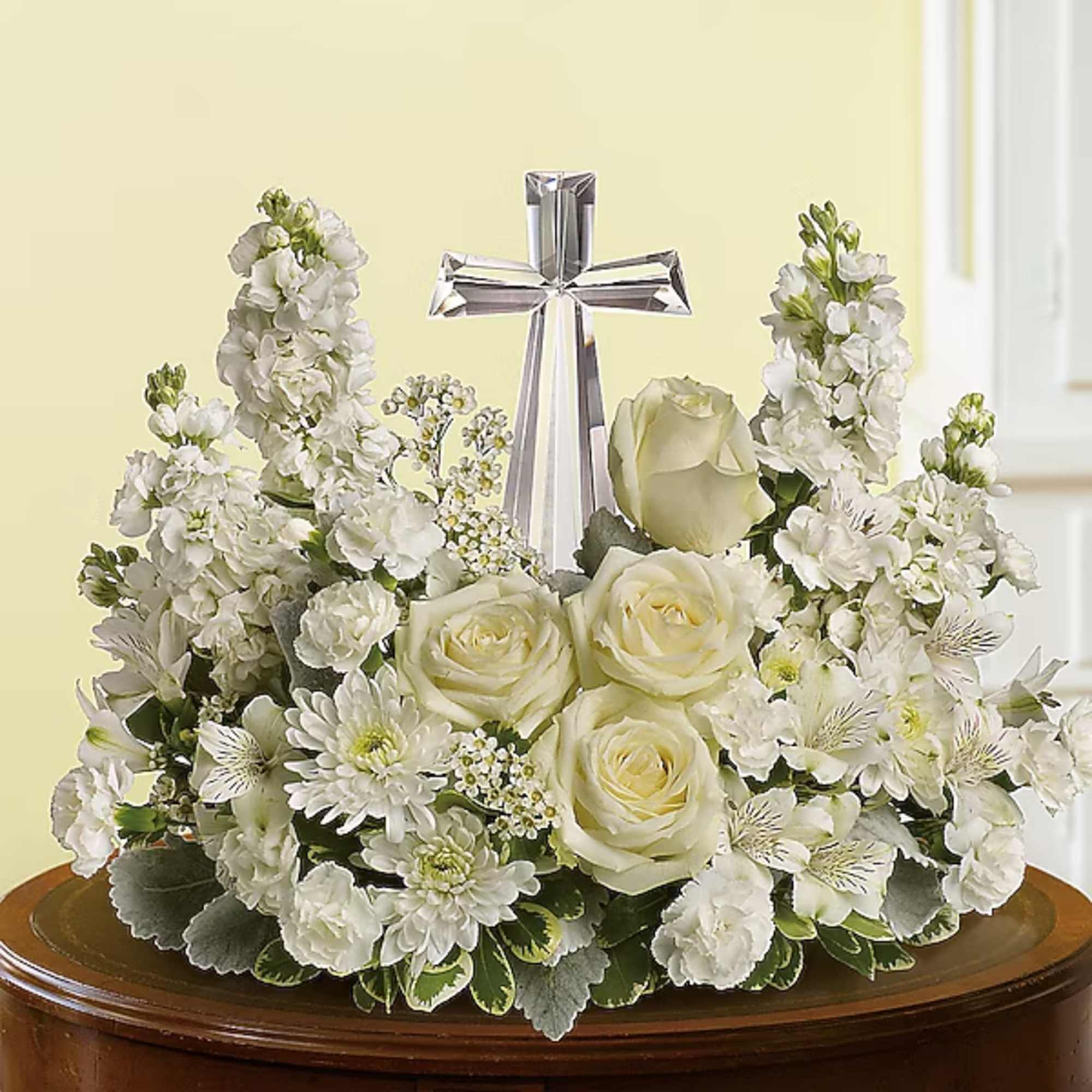 White floral arrangement with roses and a silver cross centerpiece