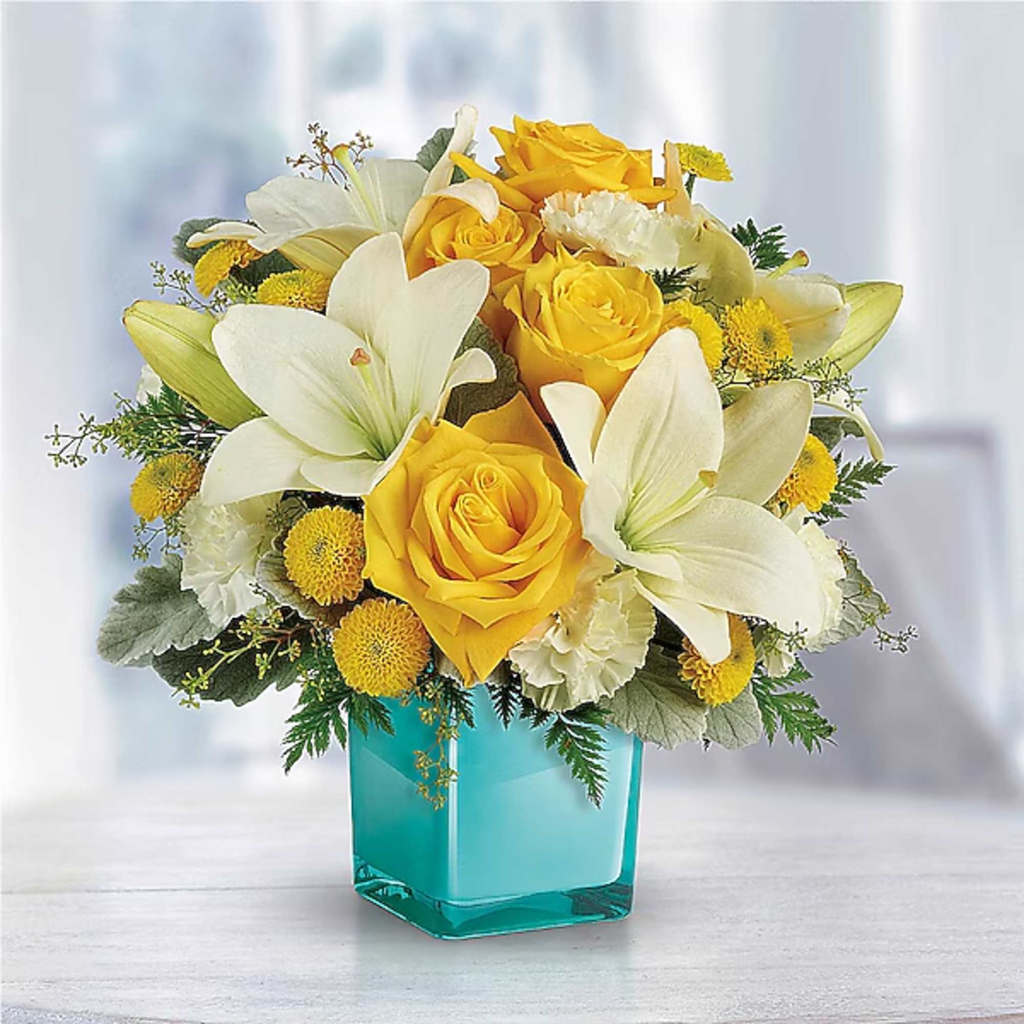 Yellow roses and white lilies in a turquoise glass vase