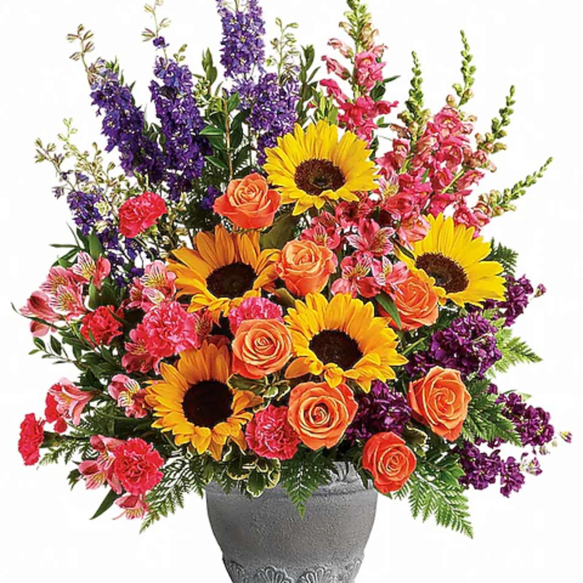 Mixed bouquet of sunflowers, orange roses, and purple flowers in a gray vase
