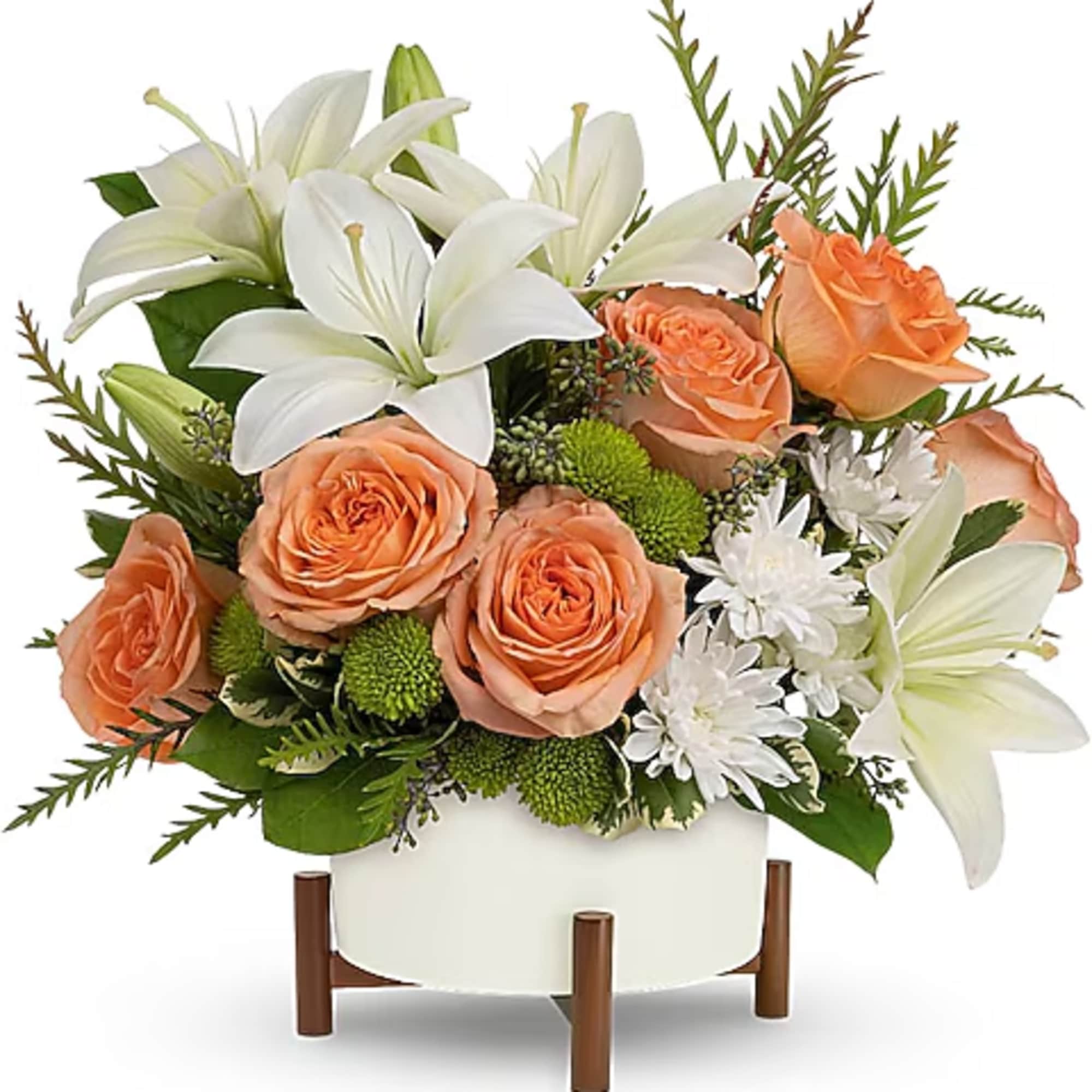 Peach roses and white lilies in a white vase with green accents