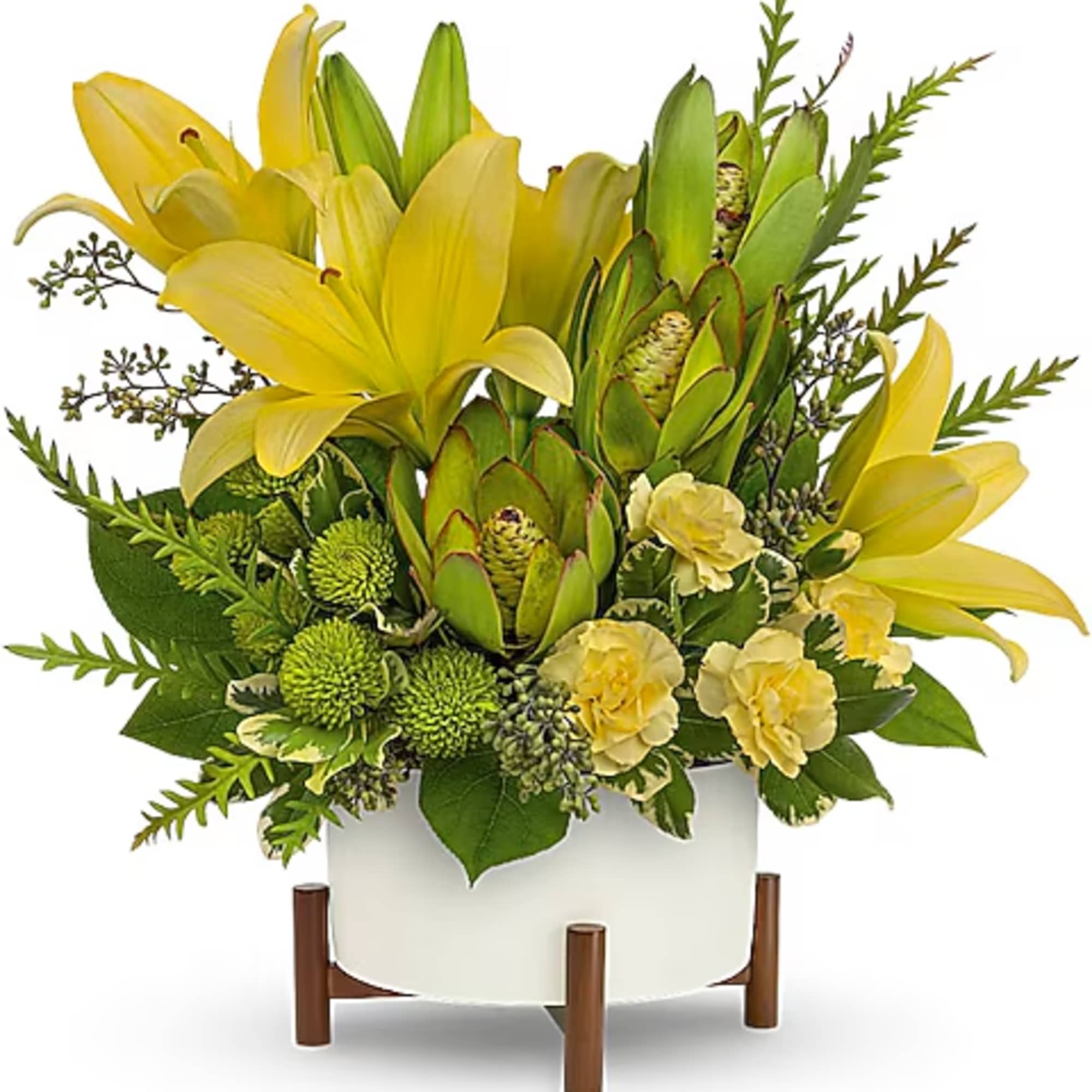 Yellow lilies and green protea in a white vase on a wooden stand