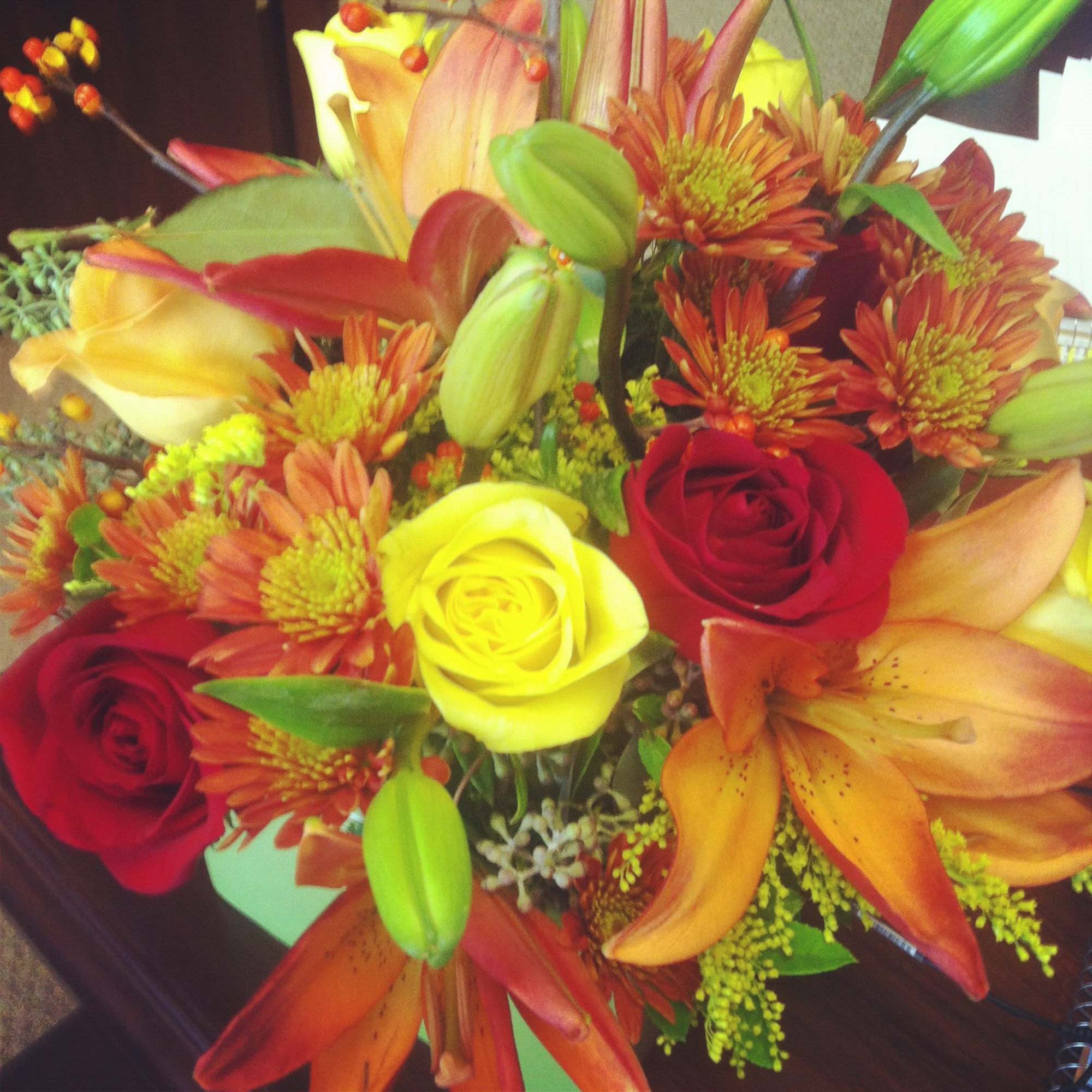 Mixed bouquet with red and yellow roses, orange lilies, and orange chrysanthemums
