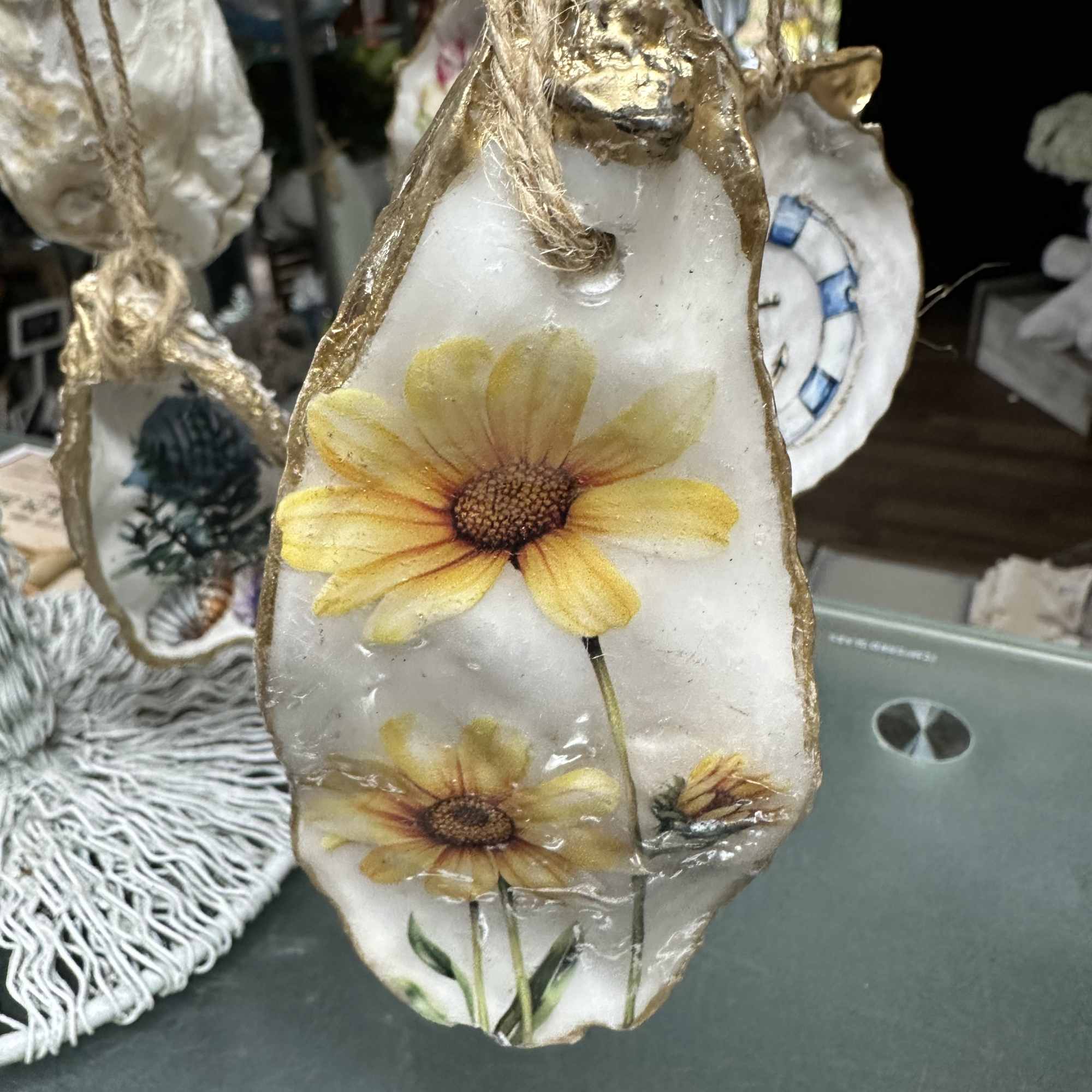 Decorative hanging shell ornament with painted yellow daisies