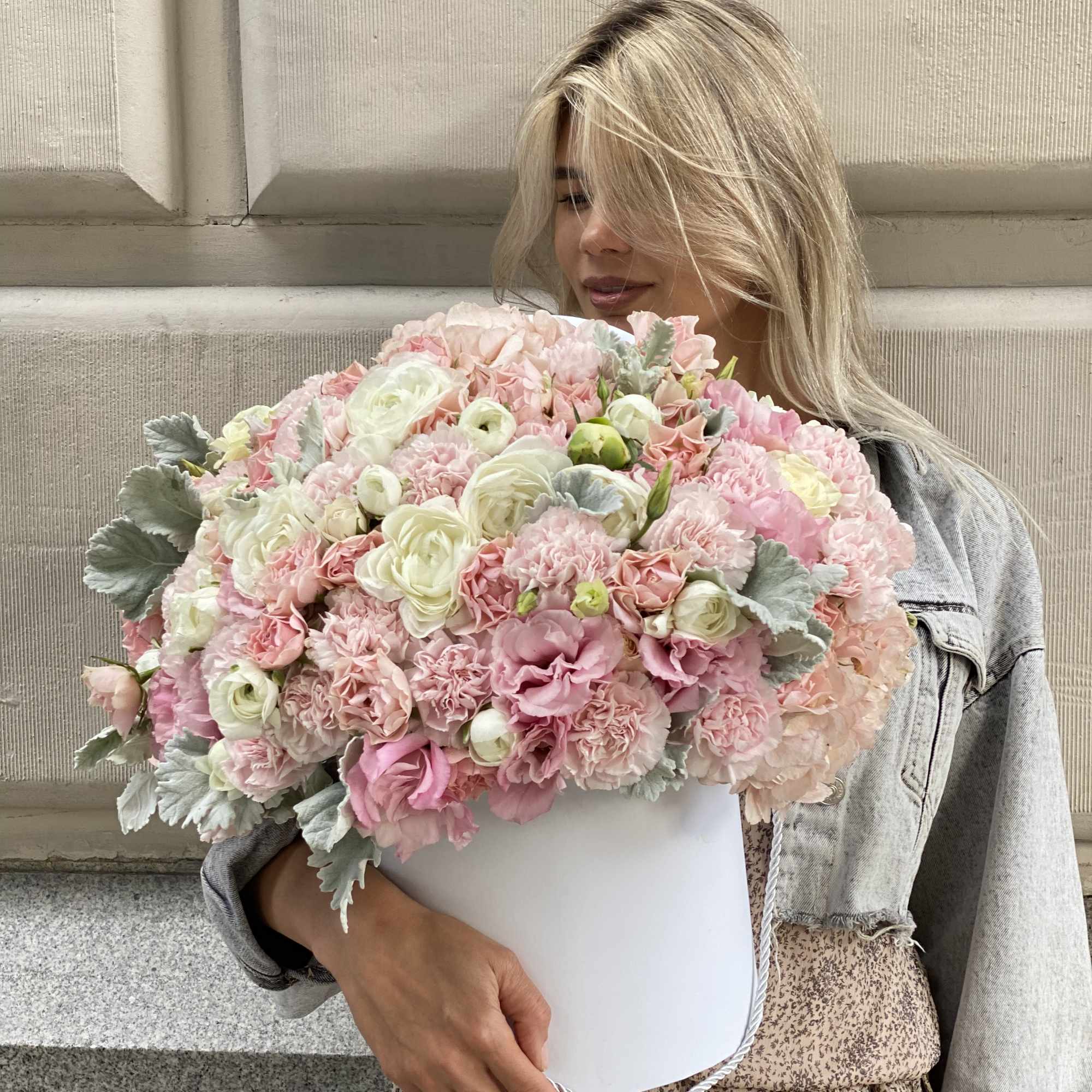 Woman holding a large pastel pink and white bouquet in a white box