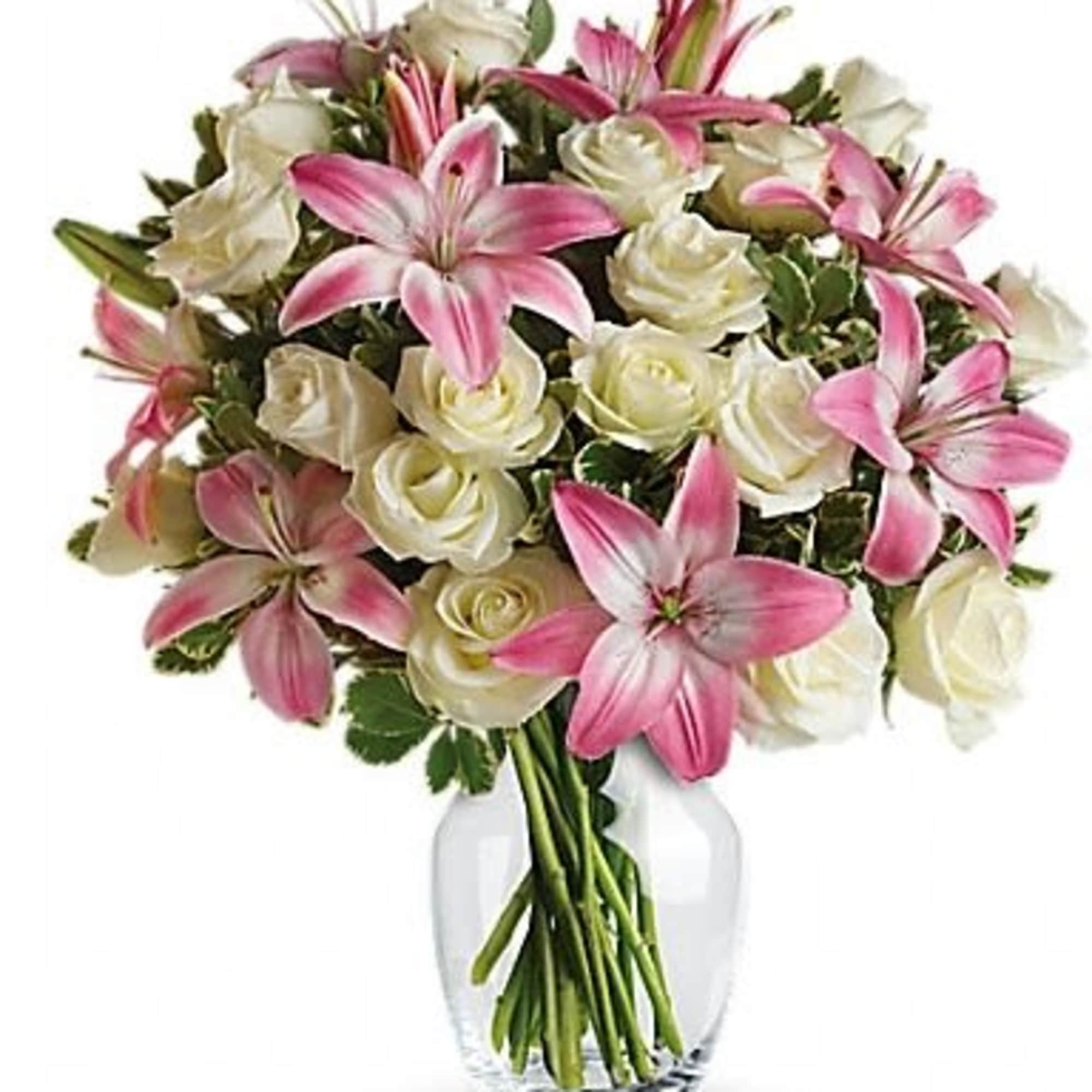 Pink lilies and white roses arranged in a clear glass vase