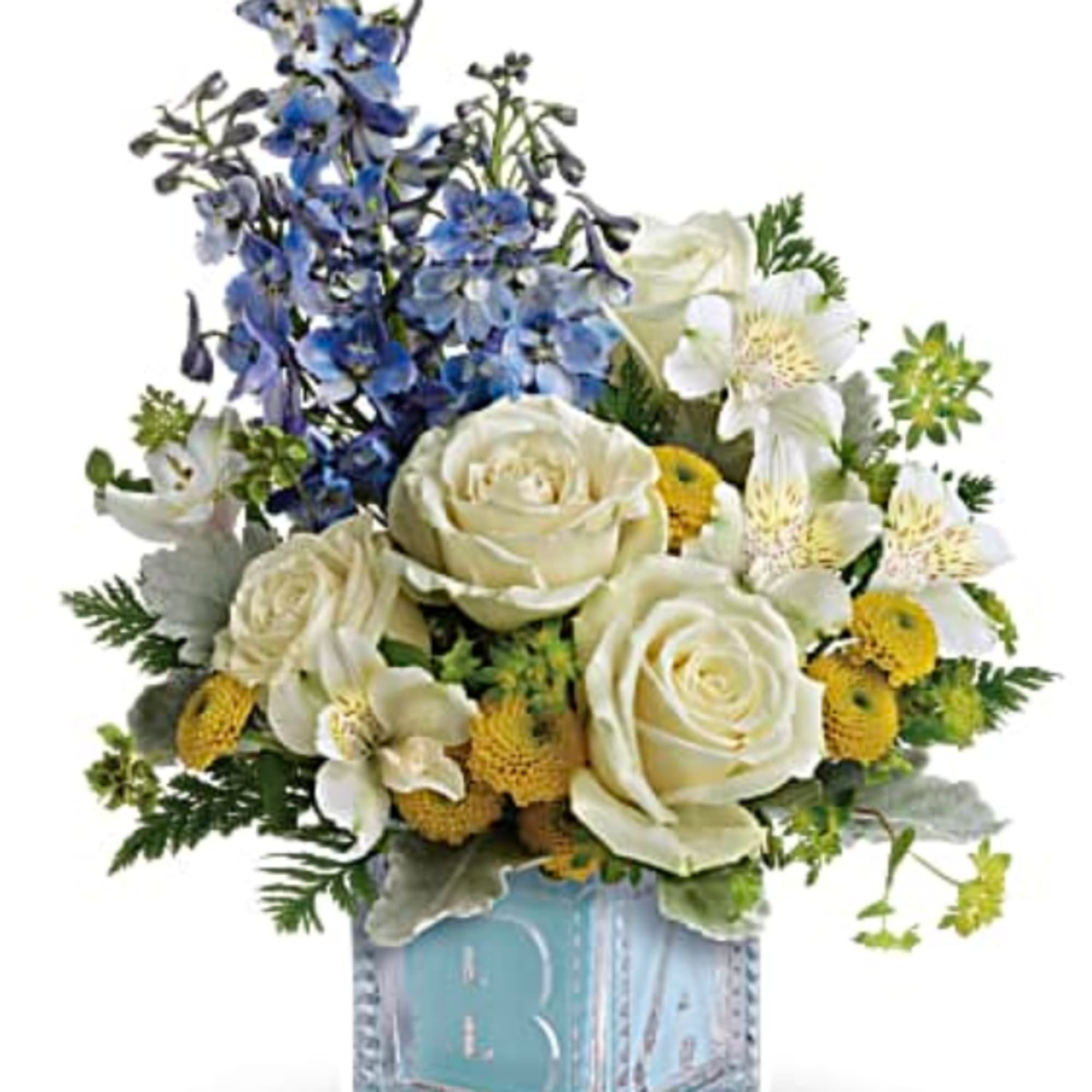 White roses and blue flowers arranged in a glass cube vase