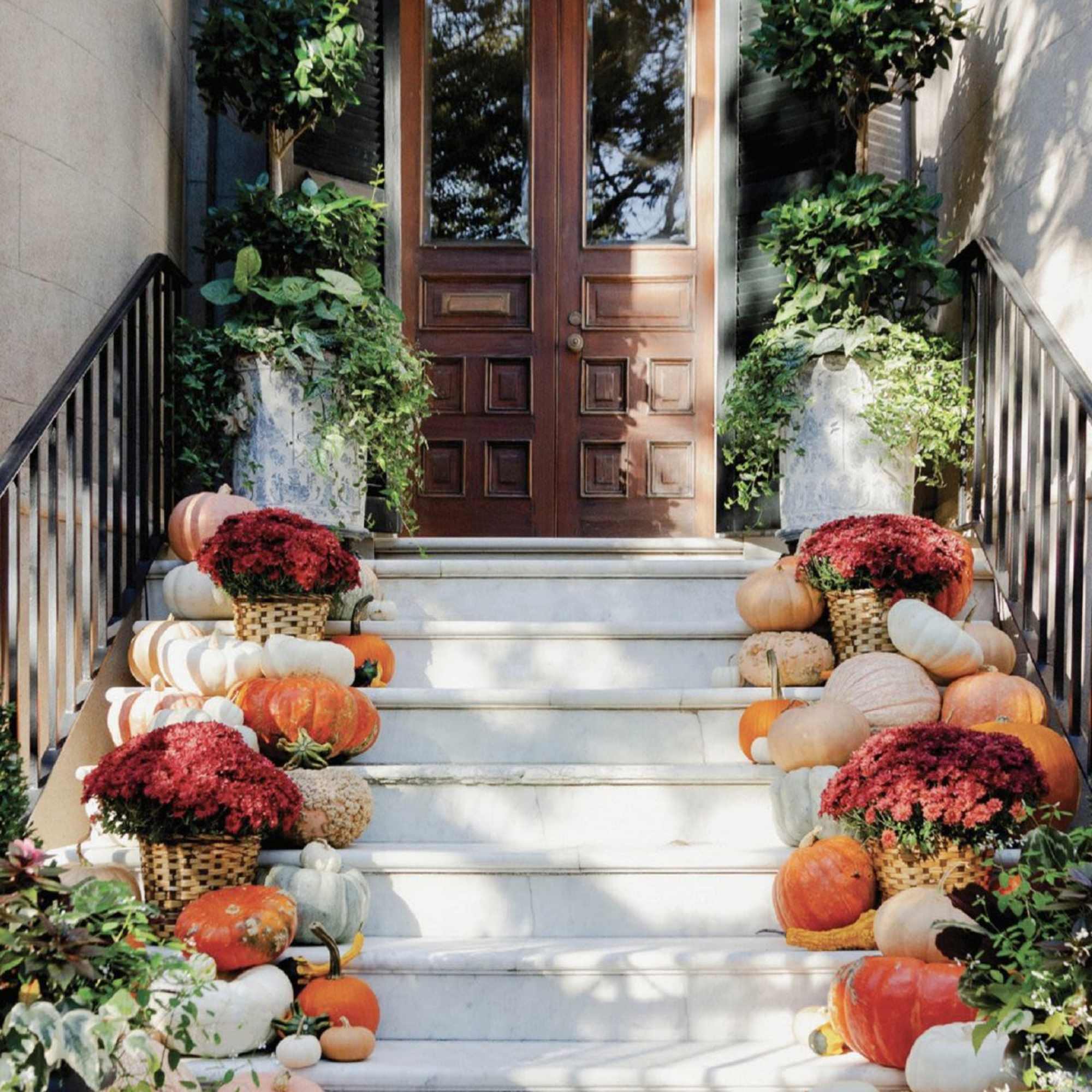 Pumpkins and potted mums decorate a front staircase