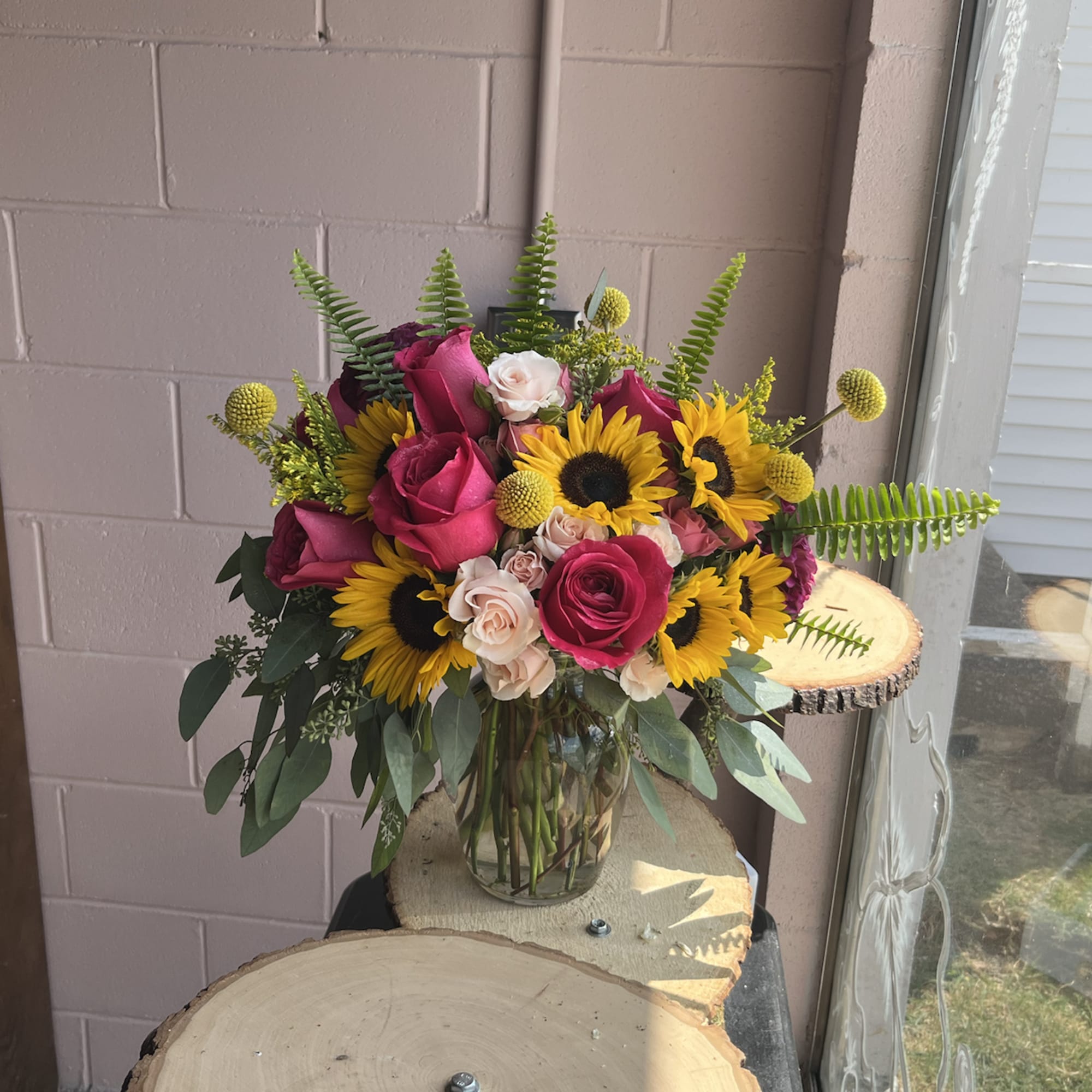 Bouquet of pink roses and sunflowers in a glass vase