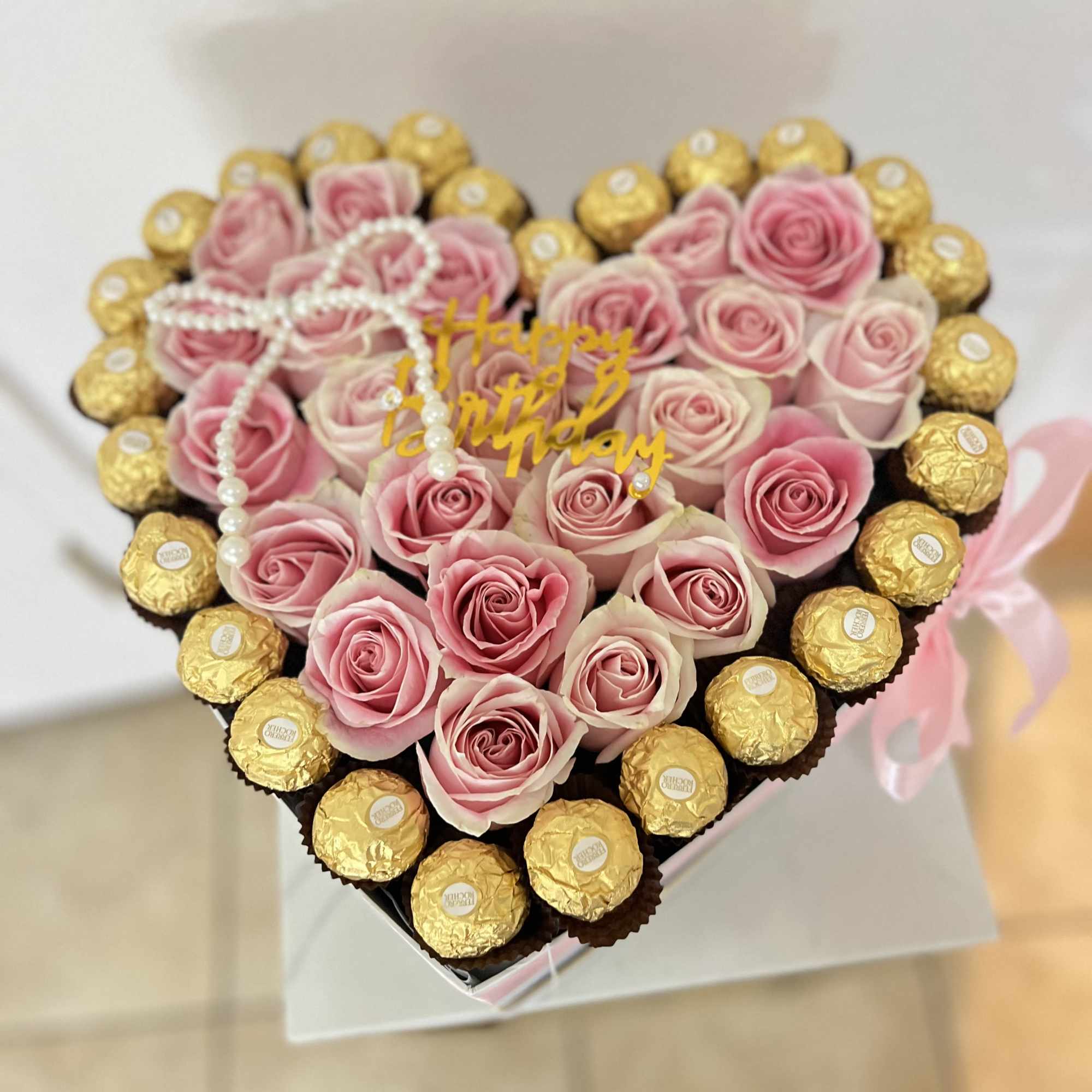 Heart-shaped box of pink roses with gold-wrapped chocolates
