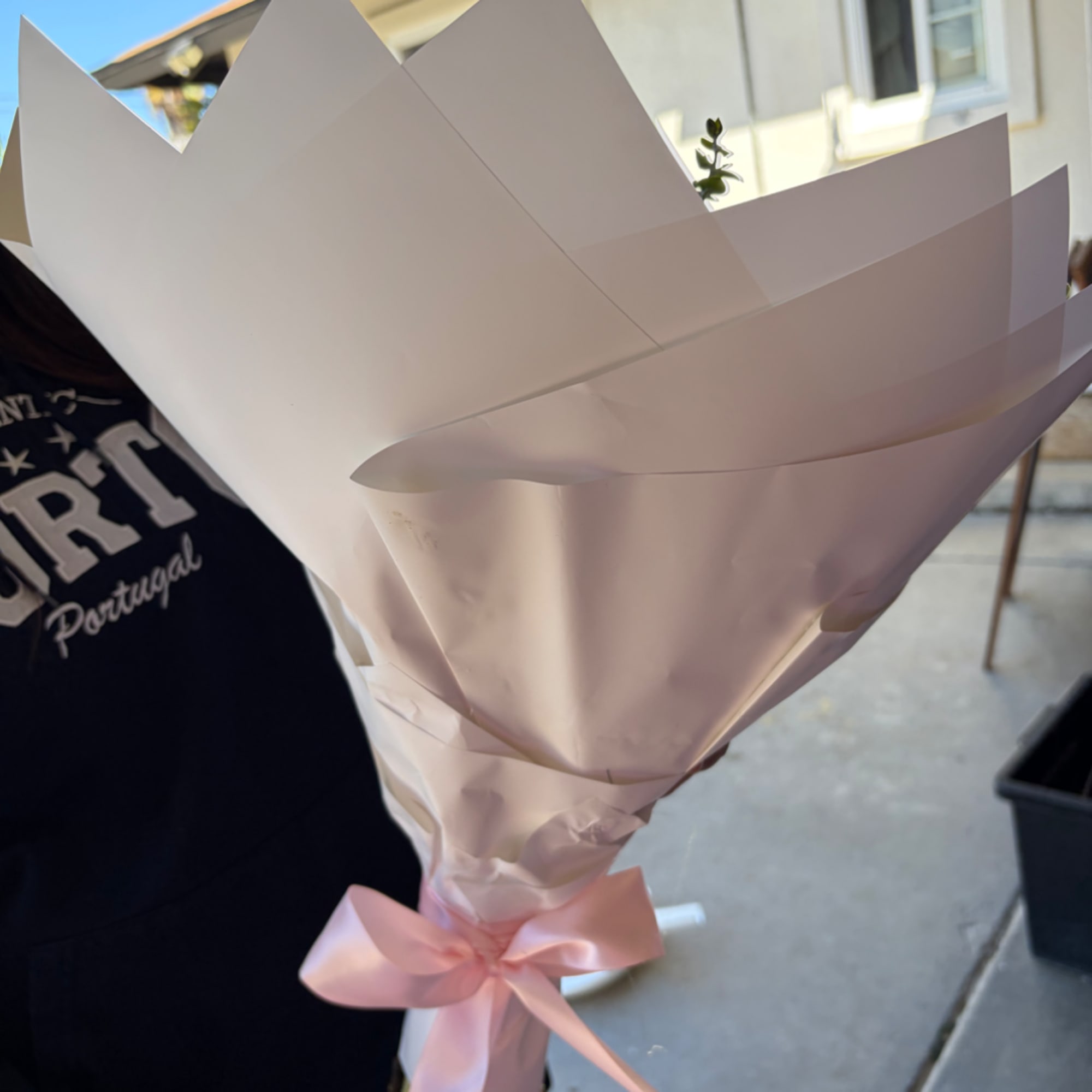 Wrapped bouquet with a pink ribbon, mostly hidden by paper