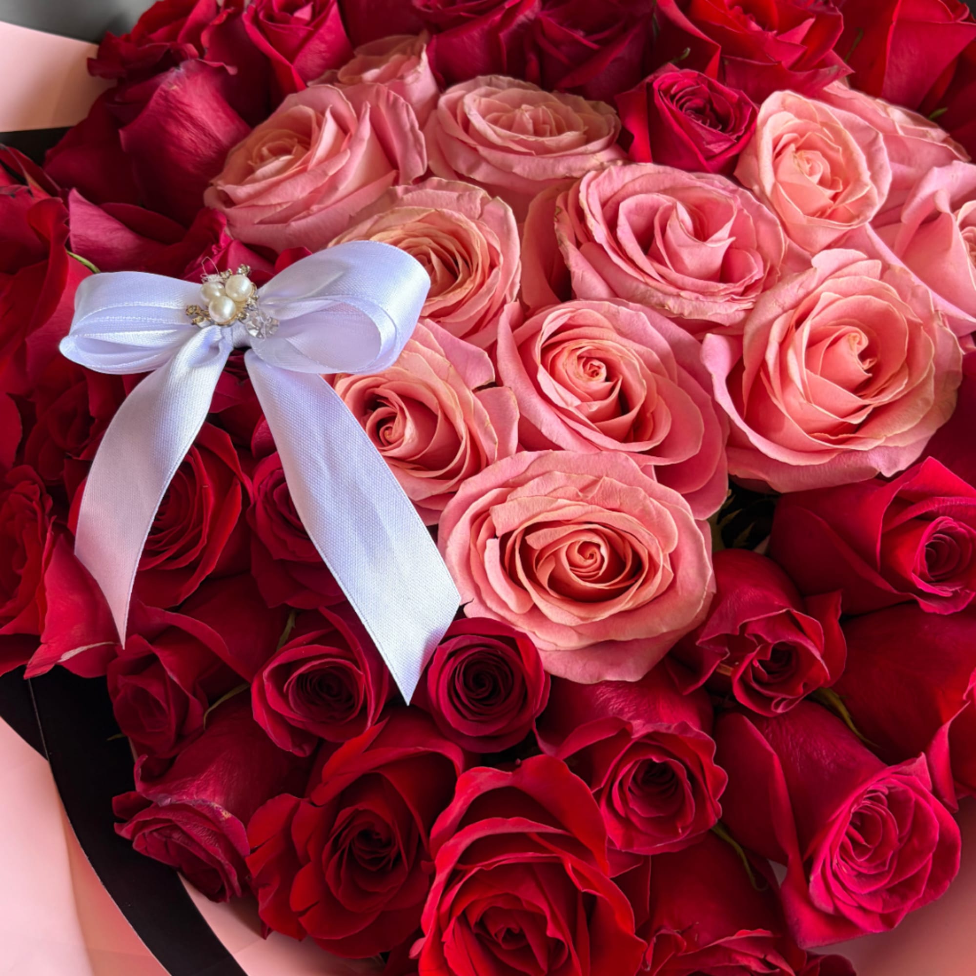 Bouquet of pink and red roses with a white ribbon bow