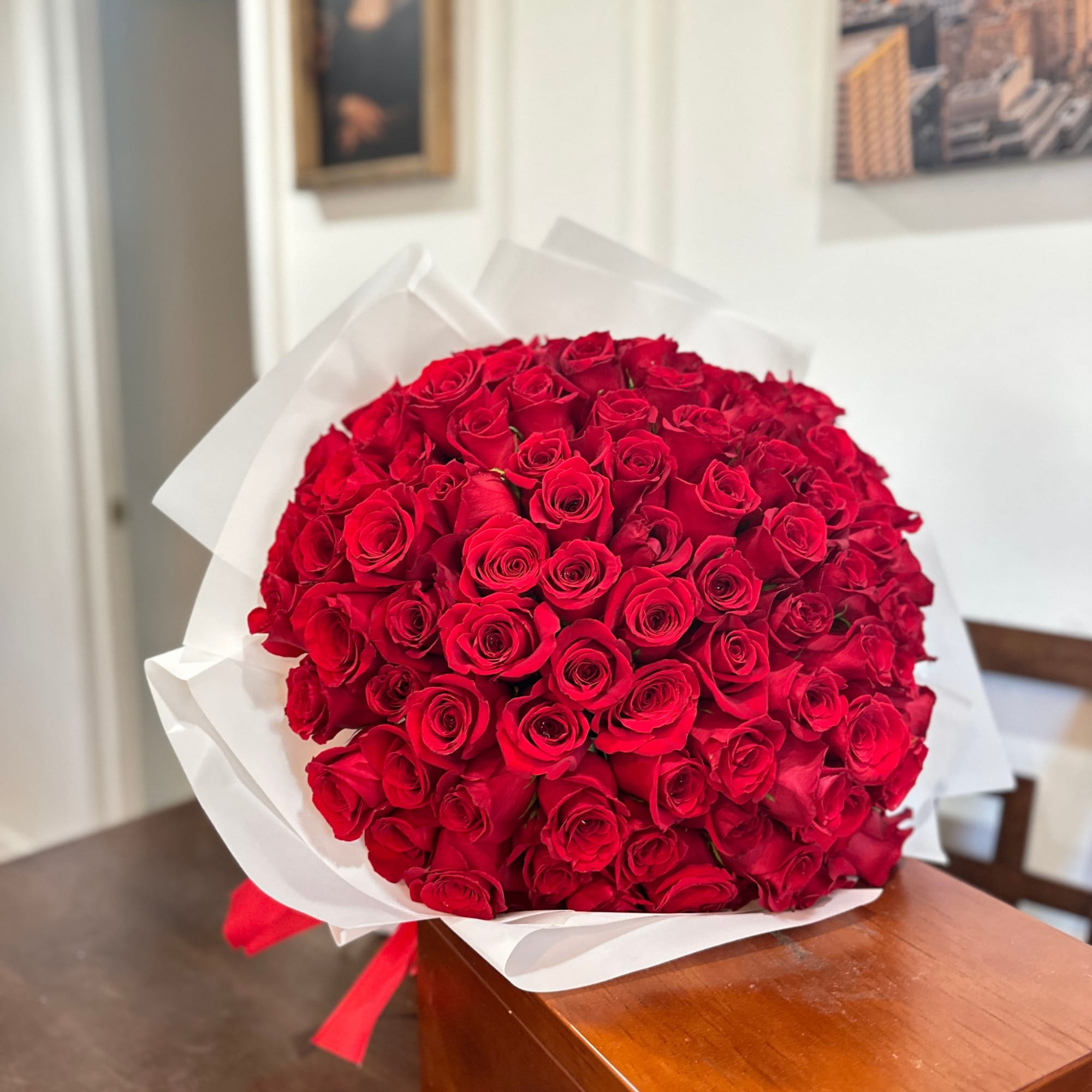 Large bouquet of red roses wrapped in white paper with a red ribbon, photo 2 of 7
