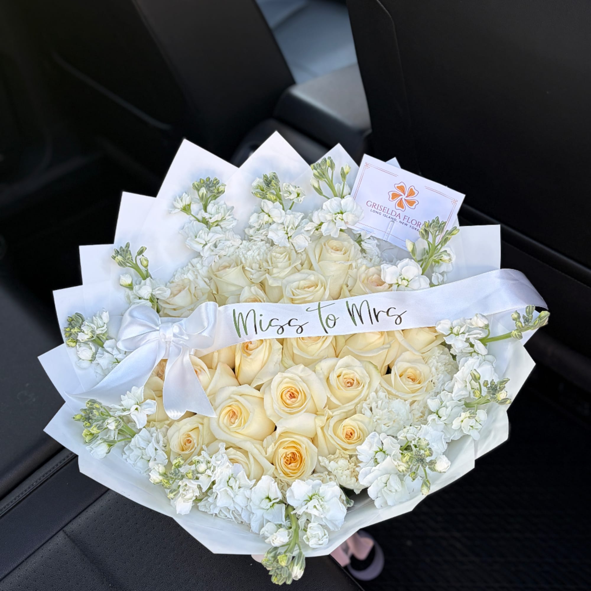 Cream rose bouquet with white flowers and a satin ribbon reading "Miss to Mrs"