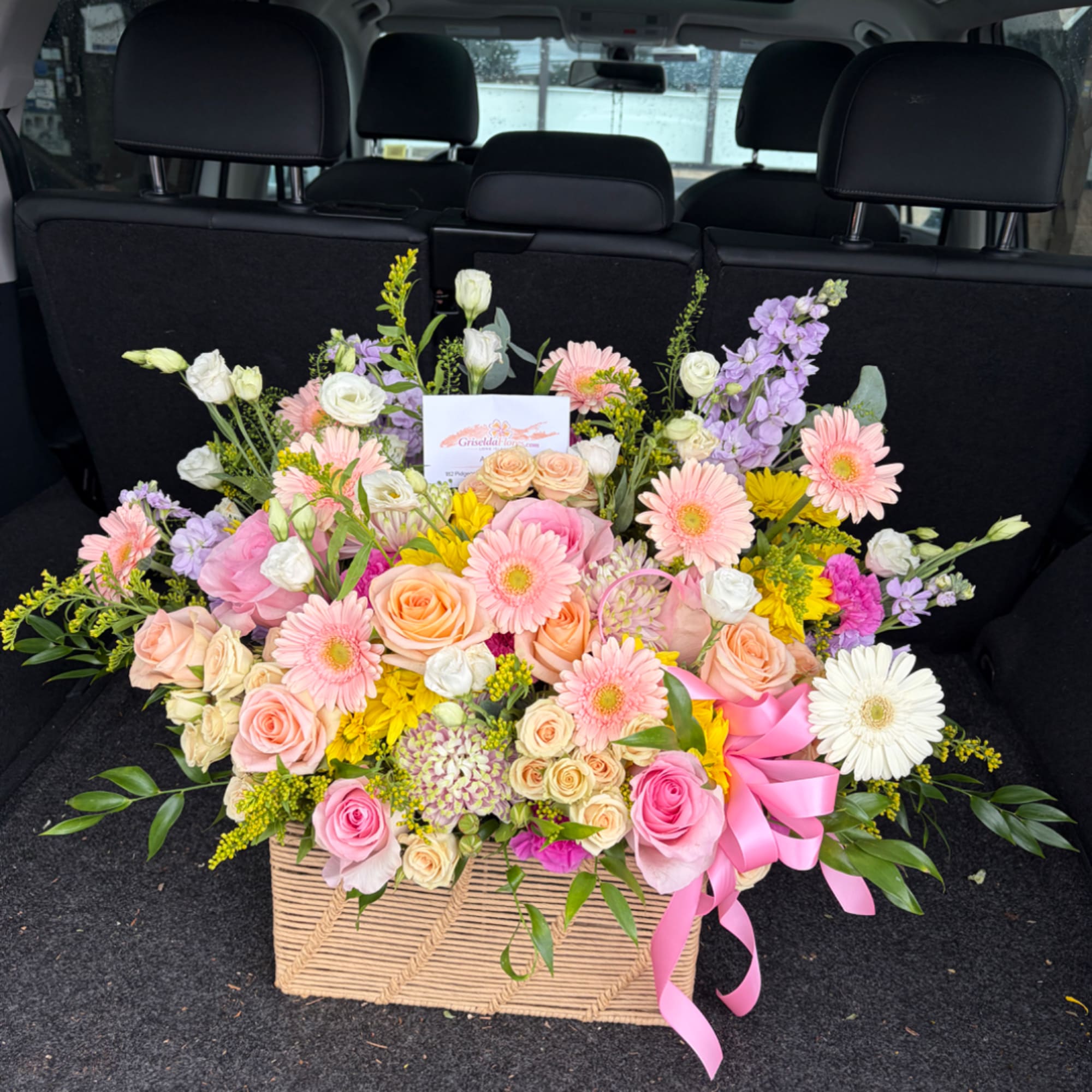 Large mixed flower arrangement in a woven basket with a pink ribbon, photo 2 of 3