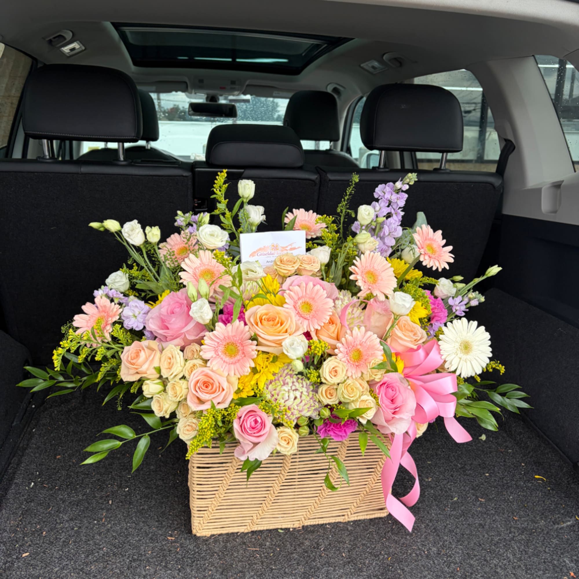 Large mixed flower arrangement in a woven basket with a pink ribbon, photo 3 of 3