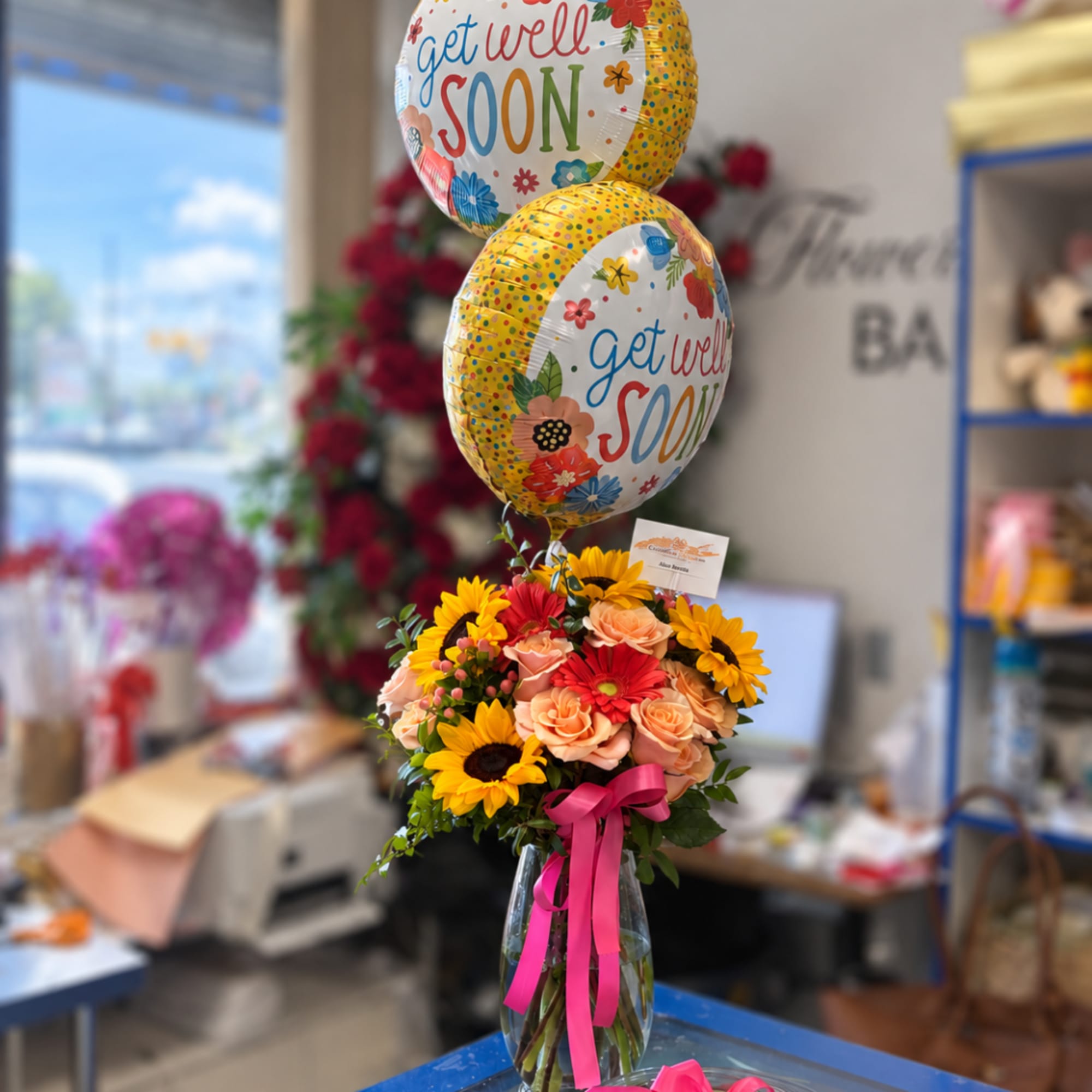 Bouquet of sunflowers, roses, and gerbera daisies with get well soon balloons